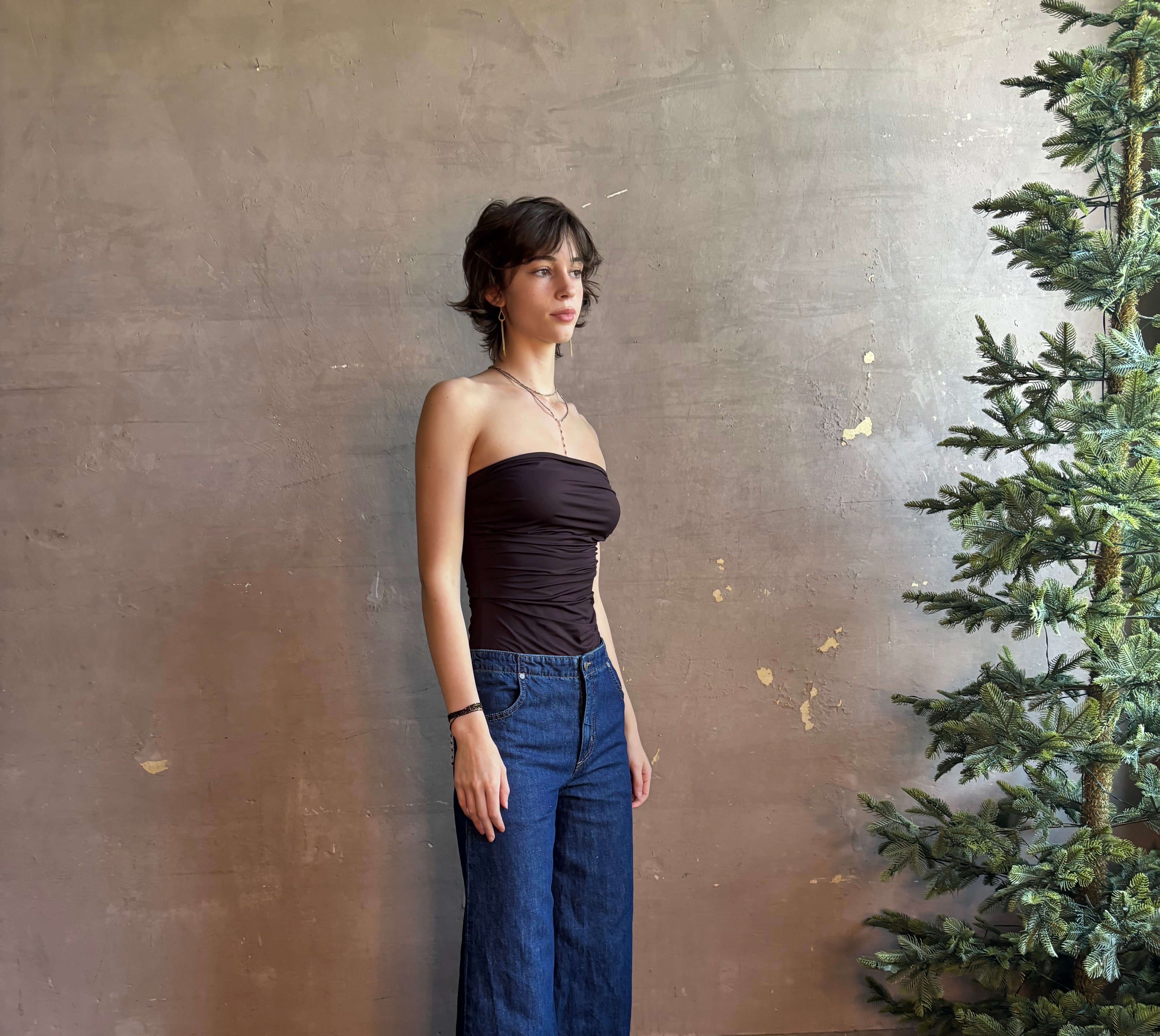Woman wearing AGOLDE Gwyneth Bodysuit in chocolate brown with premium stretch for timeless versatile styling with gathered fabric body that is very forgiving while form fitted