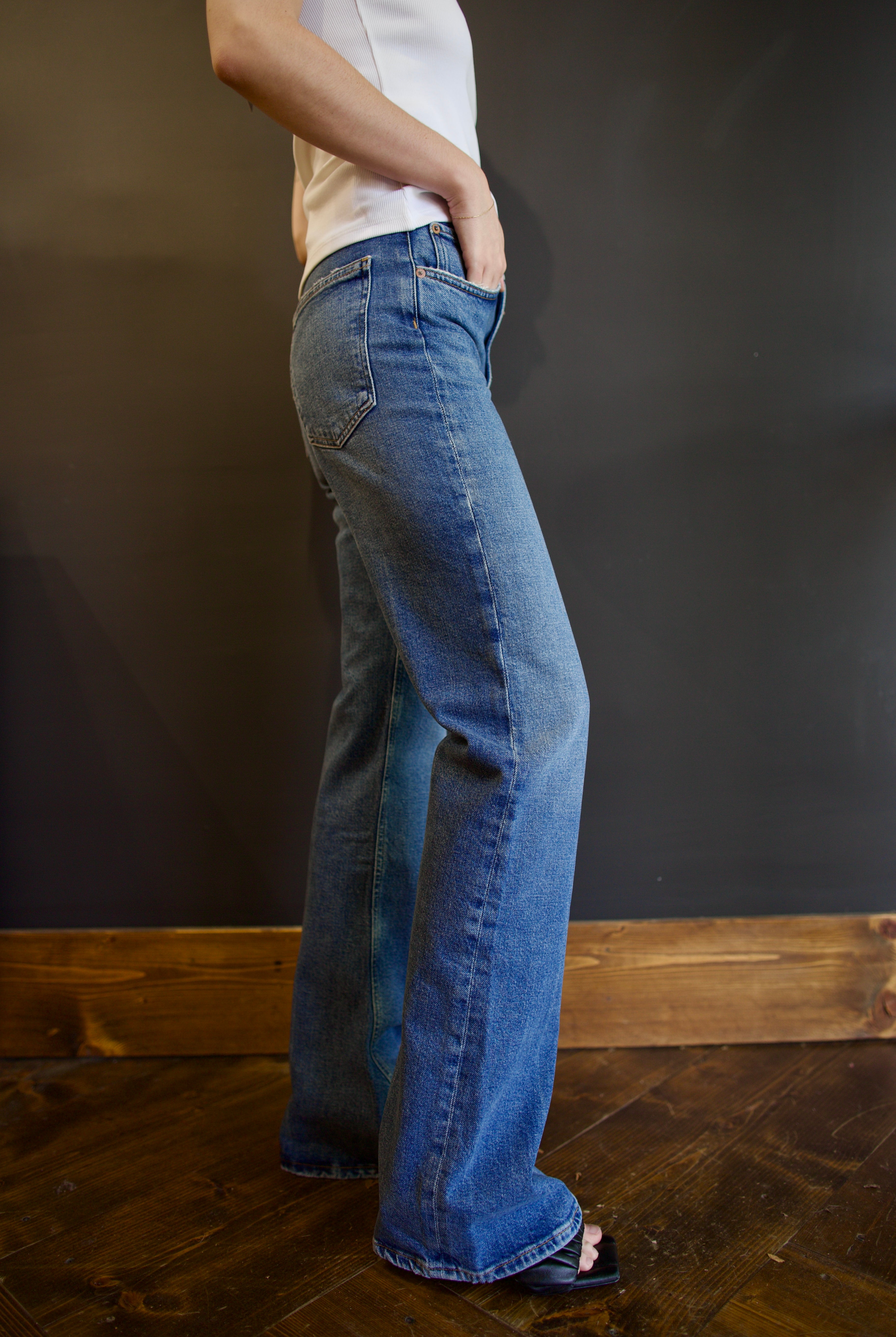 Model wearing Agolde mid-rise kick boot comfort denim in curve wash with generous inseam