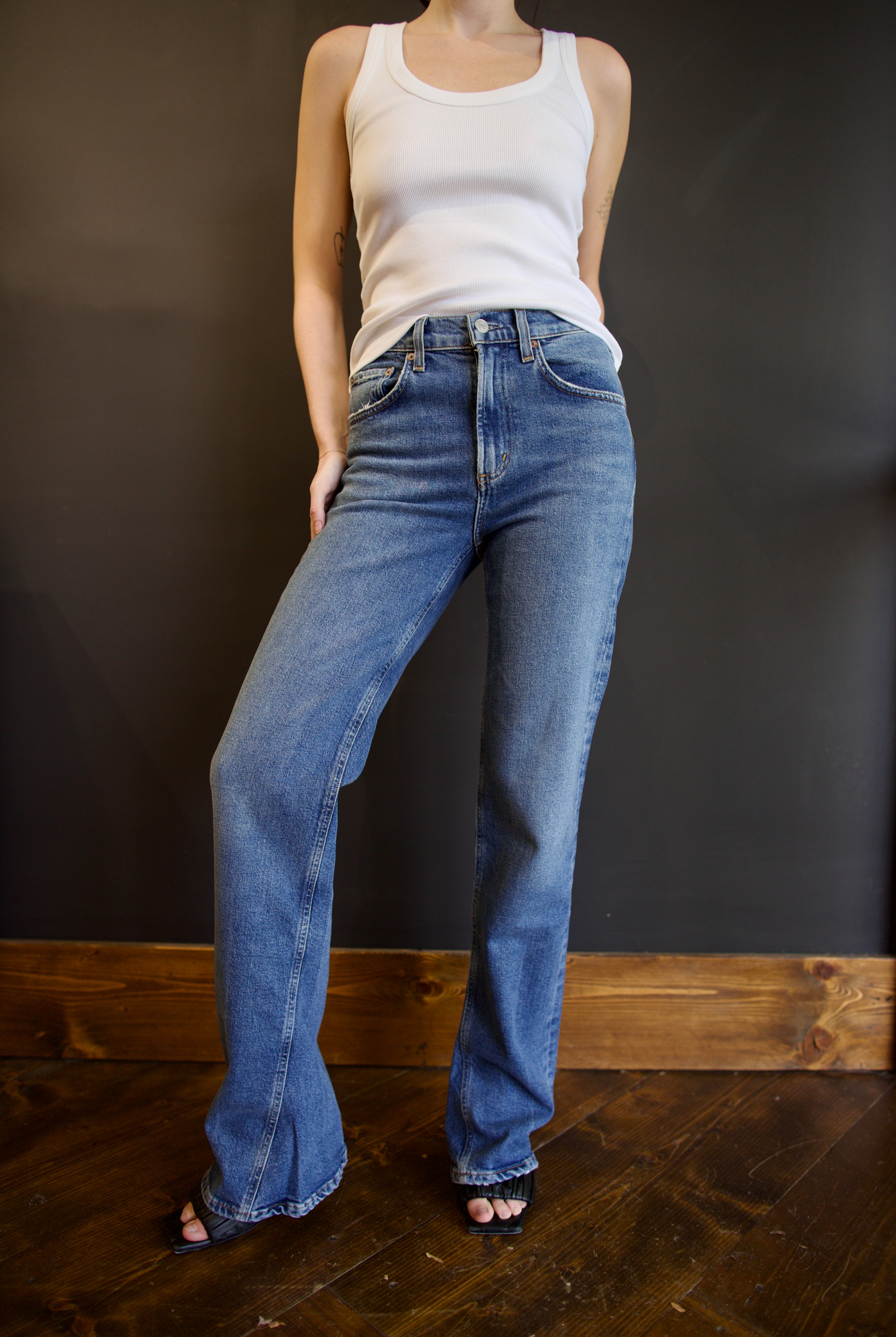 Model wearing Agolde mid-rise kick boot comfort denim in curve wash with generous inseam