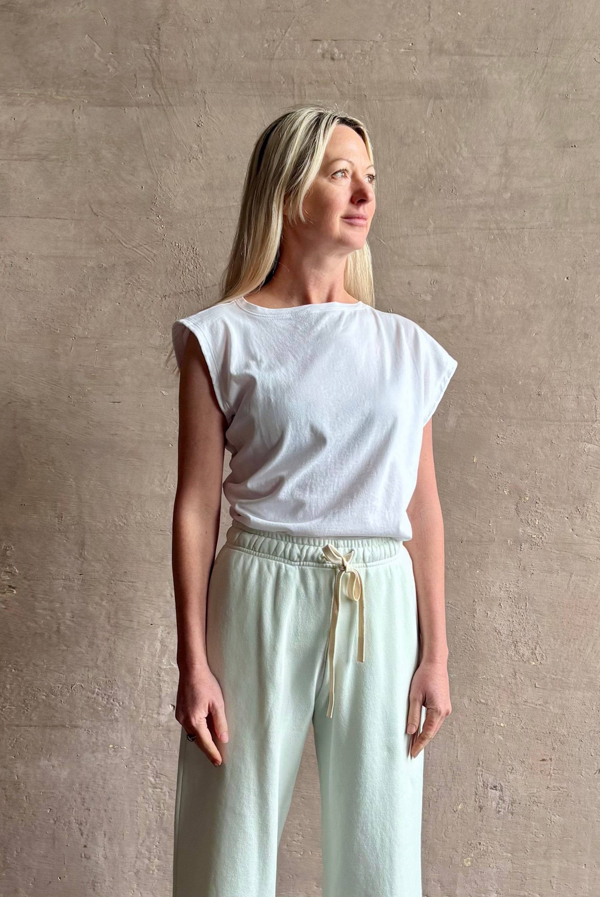 Mature woman wearing a white asymmetrical beth tee shirt from Agolde with short sleeves, crew neckline and architectural draping