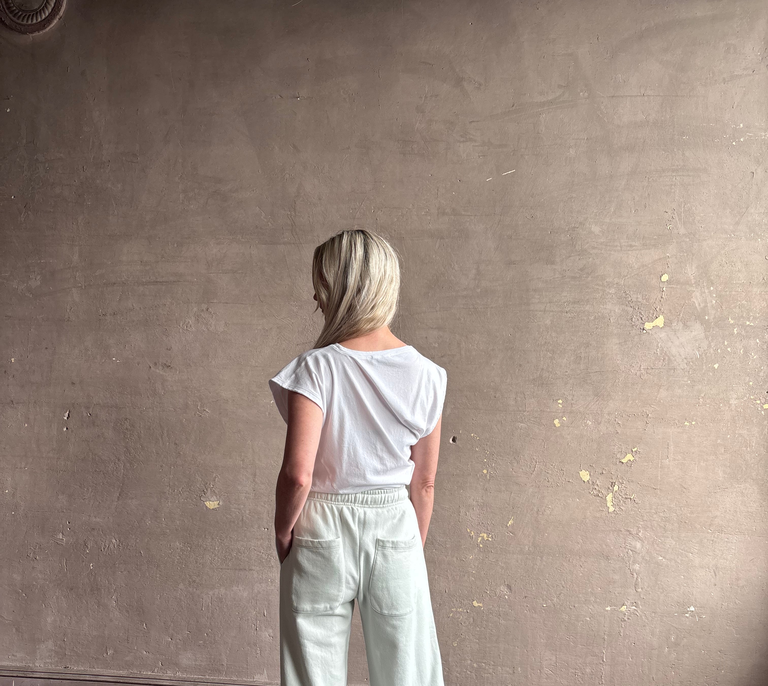 Mature woman wearing a white asymmetrical beth tee shirt from Agolde with short sleeves, crew neckline and architectural draping