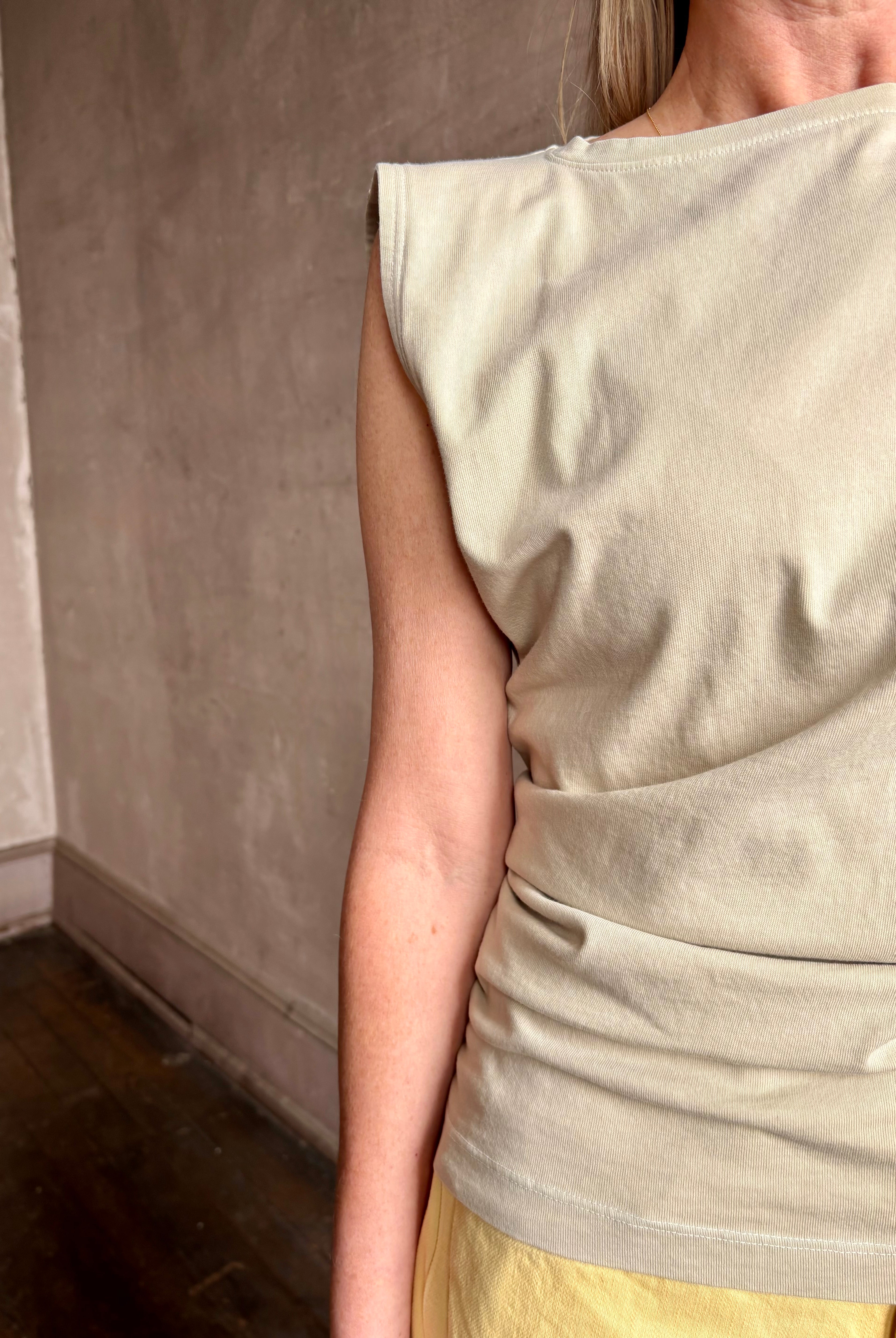 Image of woman wearing - Premium Organic Cotton Luxury Basics AGOLDE asymmetrical Beth Tee in Rice Grass beige with cap sleeves and draping