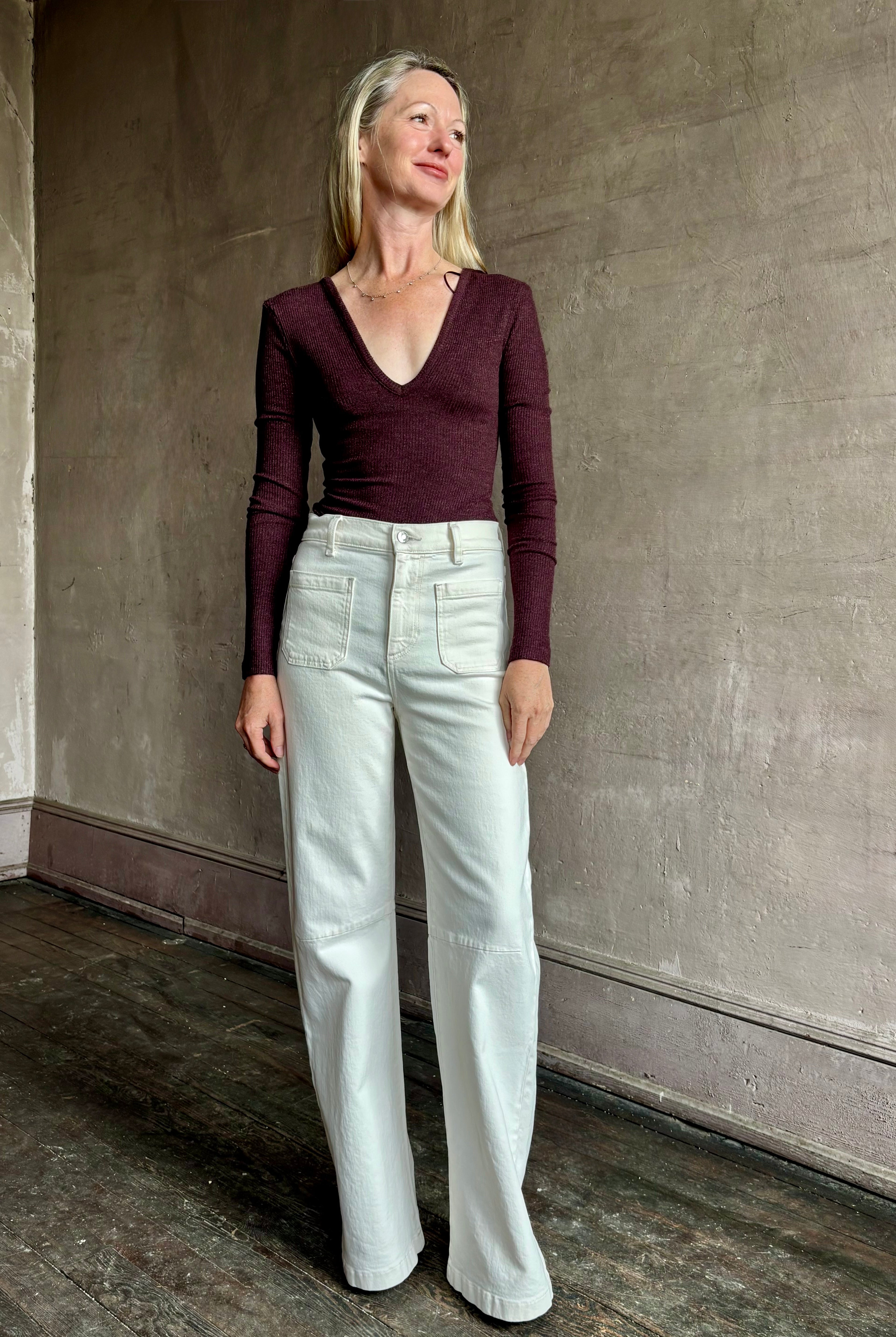 Image of woman wearing Agolde Darla Bodysuit in raisin colorway with deep v-neck and long sleeves perfect for layering