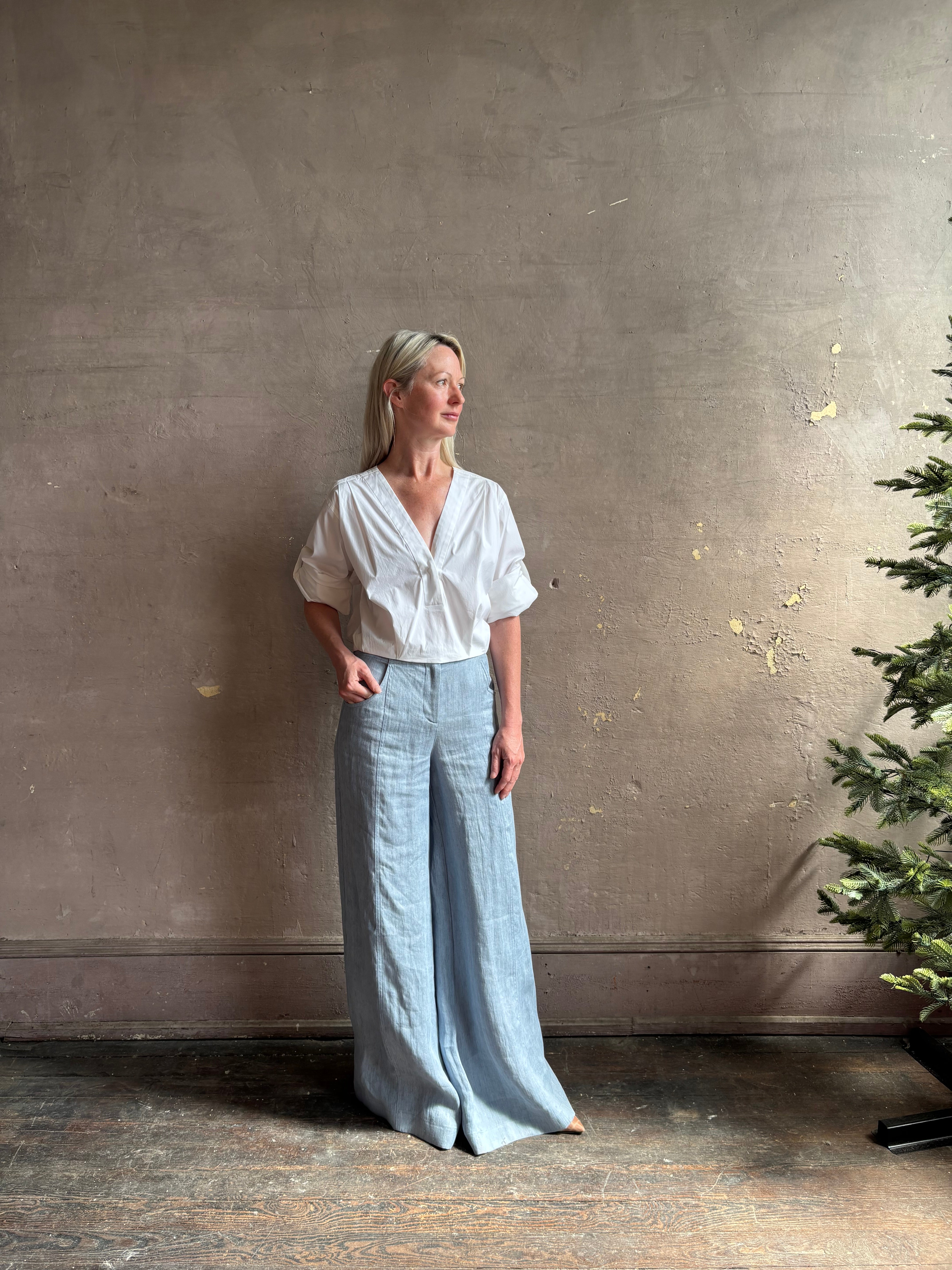 Mature woman wearing The A.L.C. Jordan Top in White Long sleeve blouse boasts premium cotton blend with v-neck and tab to roll sleeves up to a half sleeve