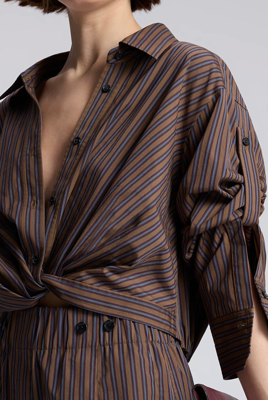 Model wearing the cotton ALC Leo button down shirt with brown and blue stripes and crop twist front
