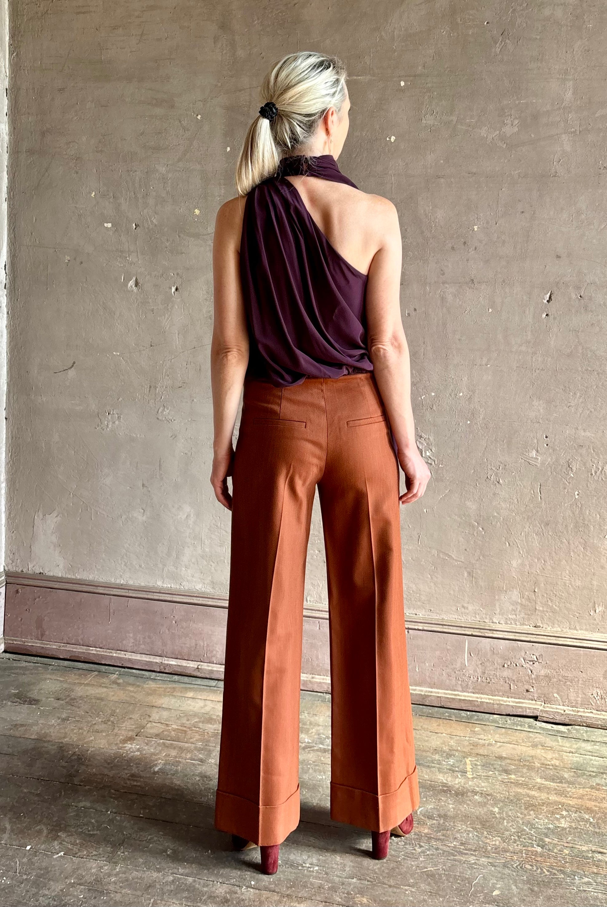 Mature model wearing ALC silk celeste deep purple top with one shoulder bubble hemline fluid draping
