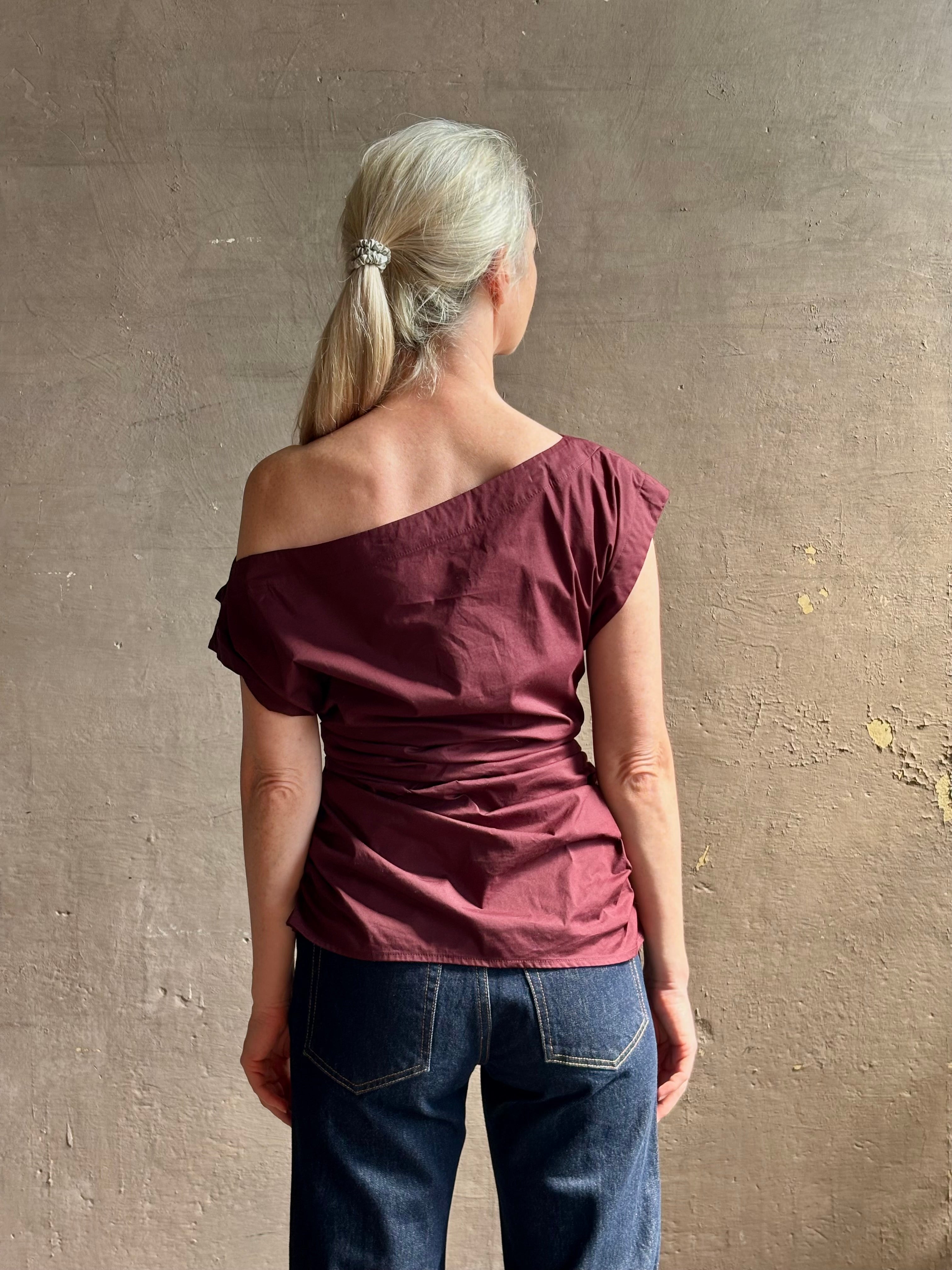 Mature woman wearing A.L.C.'s Nara Top in burgundy cotton poplin cold shoulder draping feminine cosmopolitan tailoring