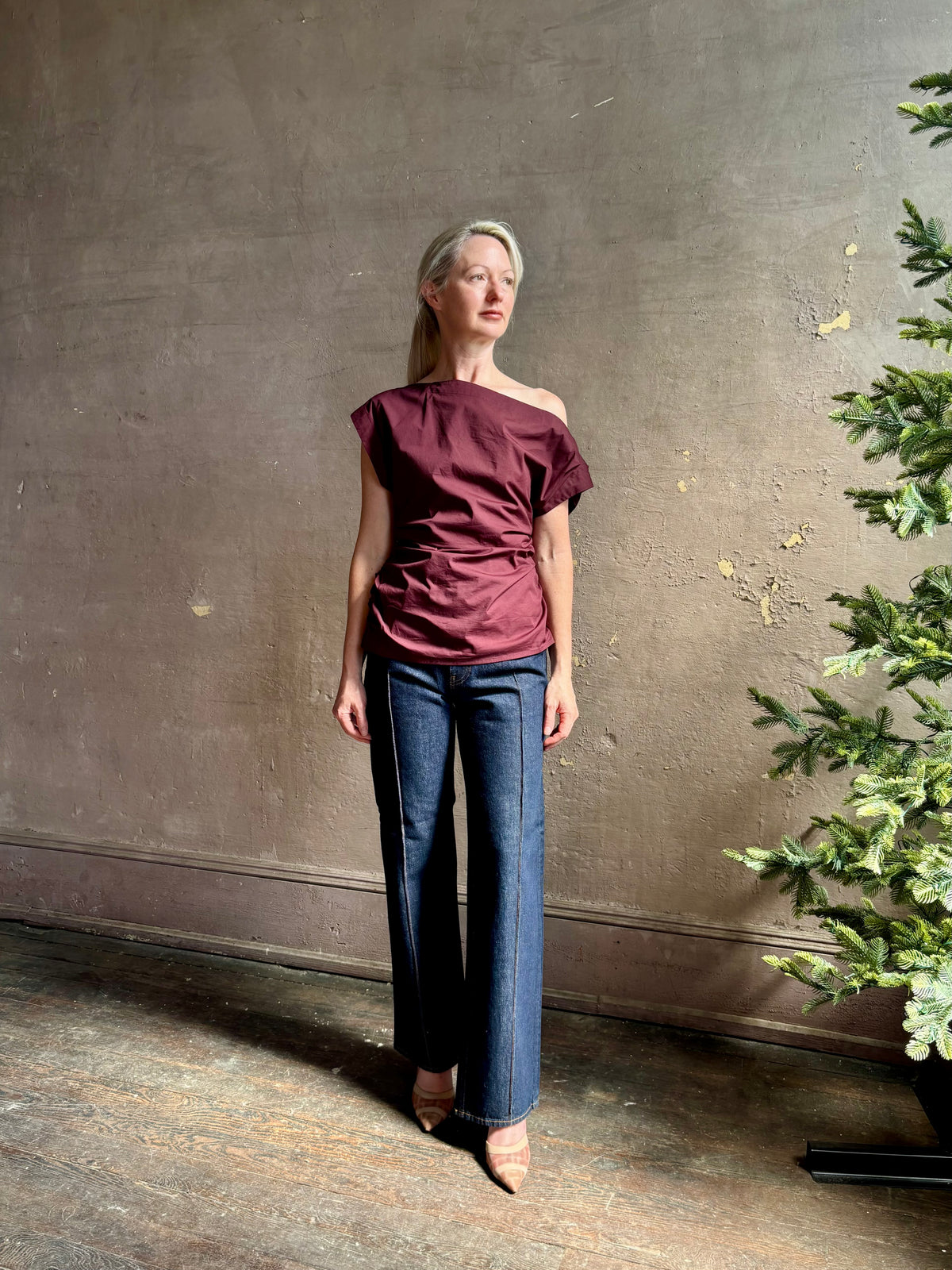 Mature woman wearing A.L.C.'s Nara Top in burgundy cotton poplin cold shoulder draping feminine cosmopolitan tailoring