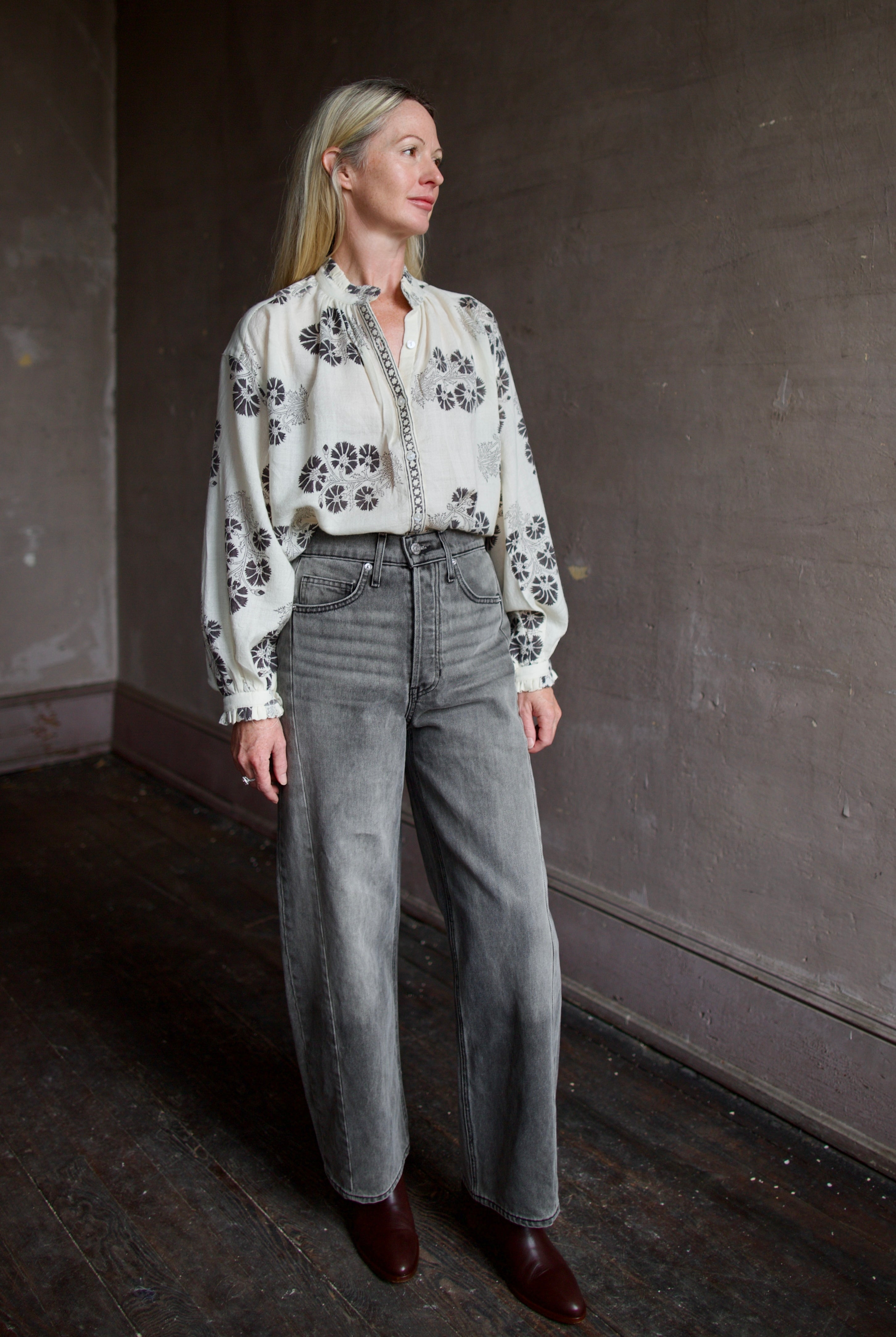 Model wearing an Alix of Bohemia wool floral blouse and Veronica Beard high-waisted grey barrel jeans.