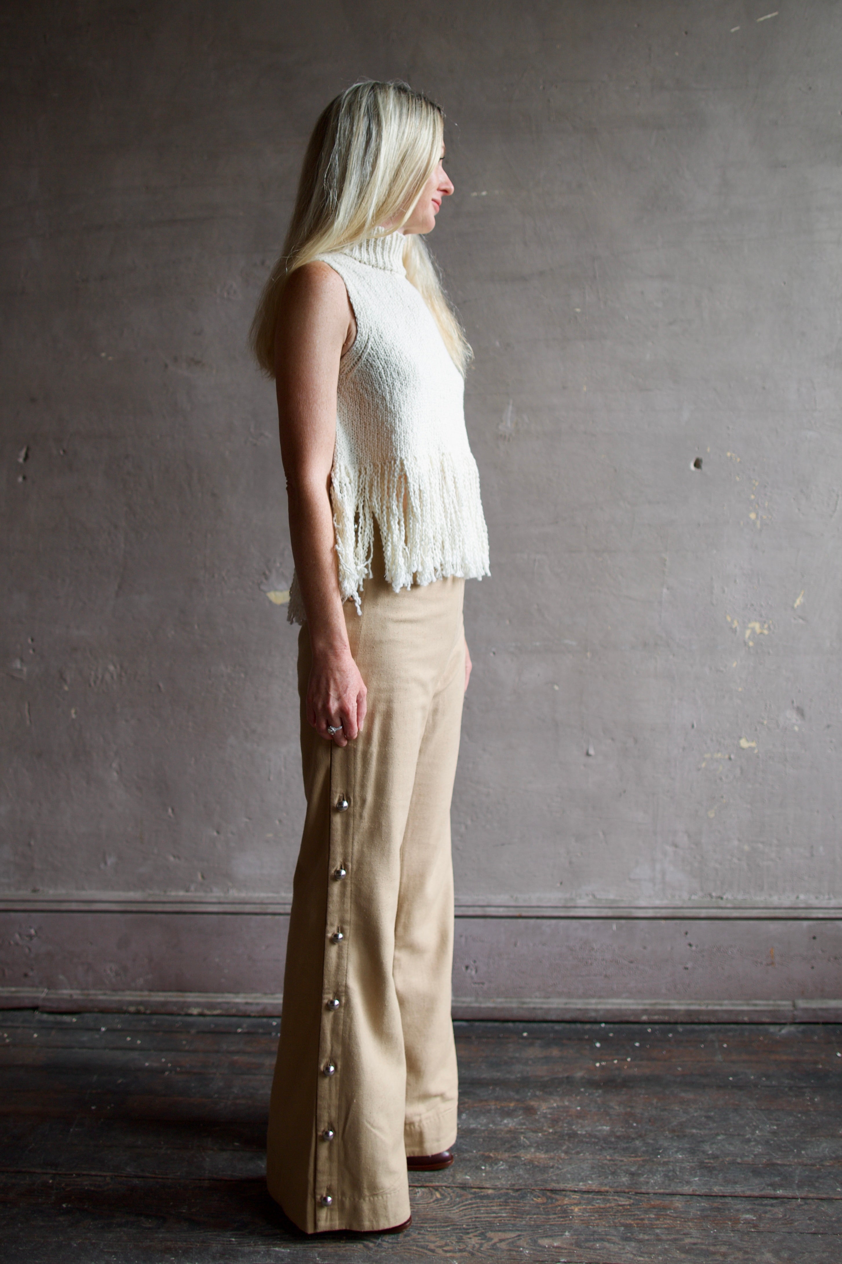 Mature woman wearing beige 100% raw silk Alix of Bohemia tailored trouser operable silver side buttons straight leg