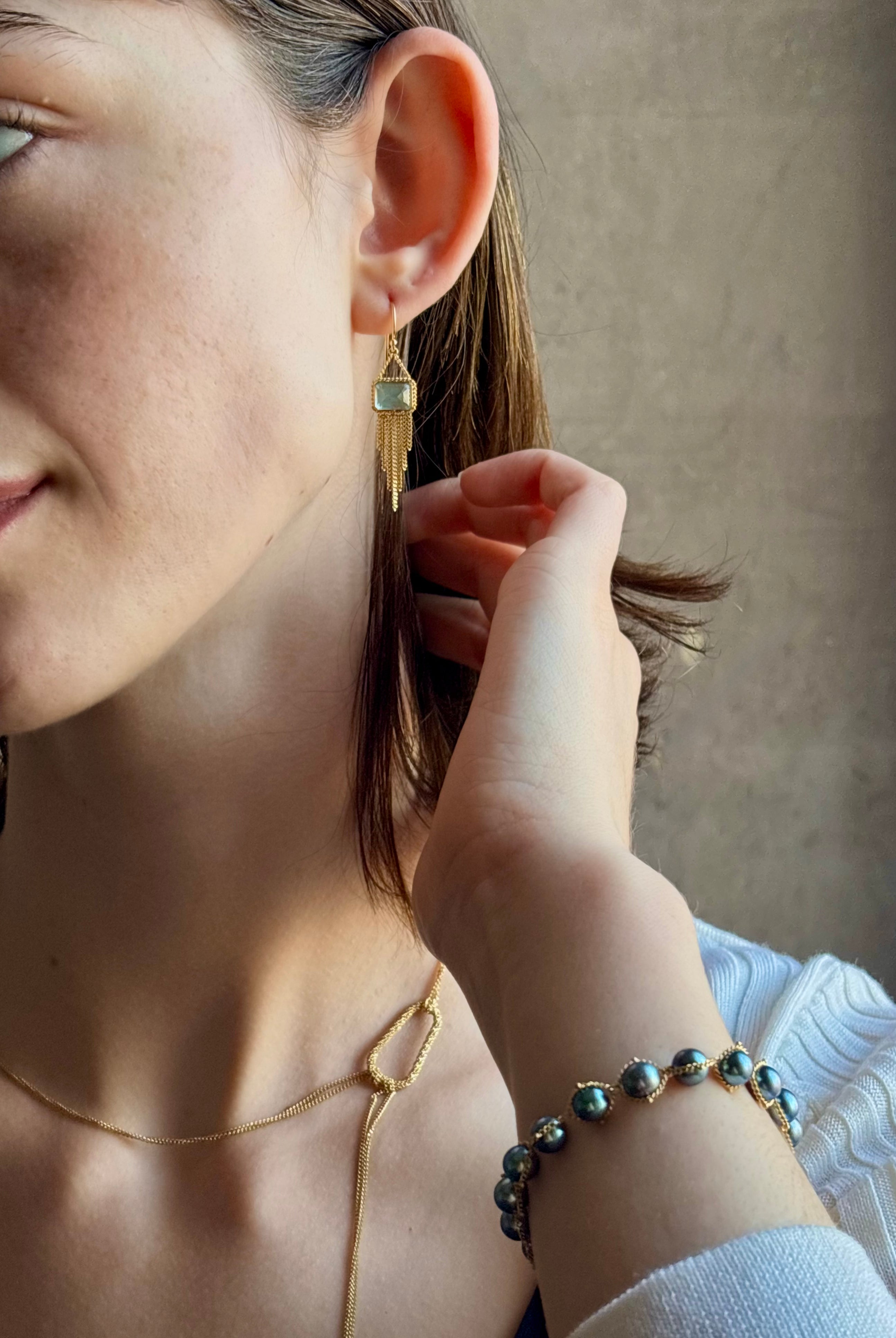 Woman wearing handmade New York designer Amali rectangular aquamarine and 18k yellow gold drop earrings with elegant gold fringe dangle embellishments