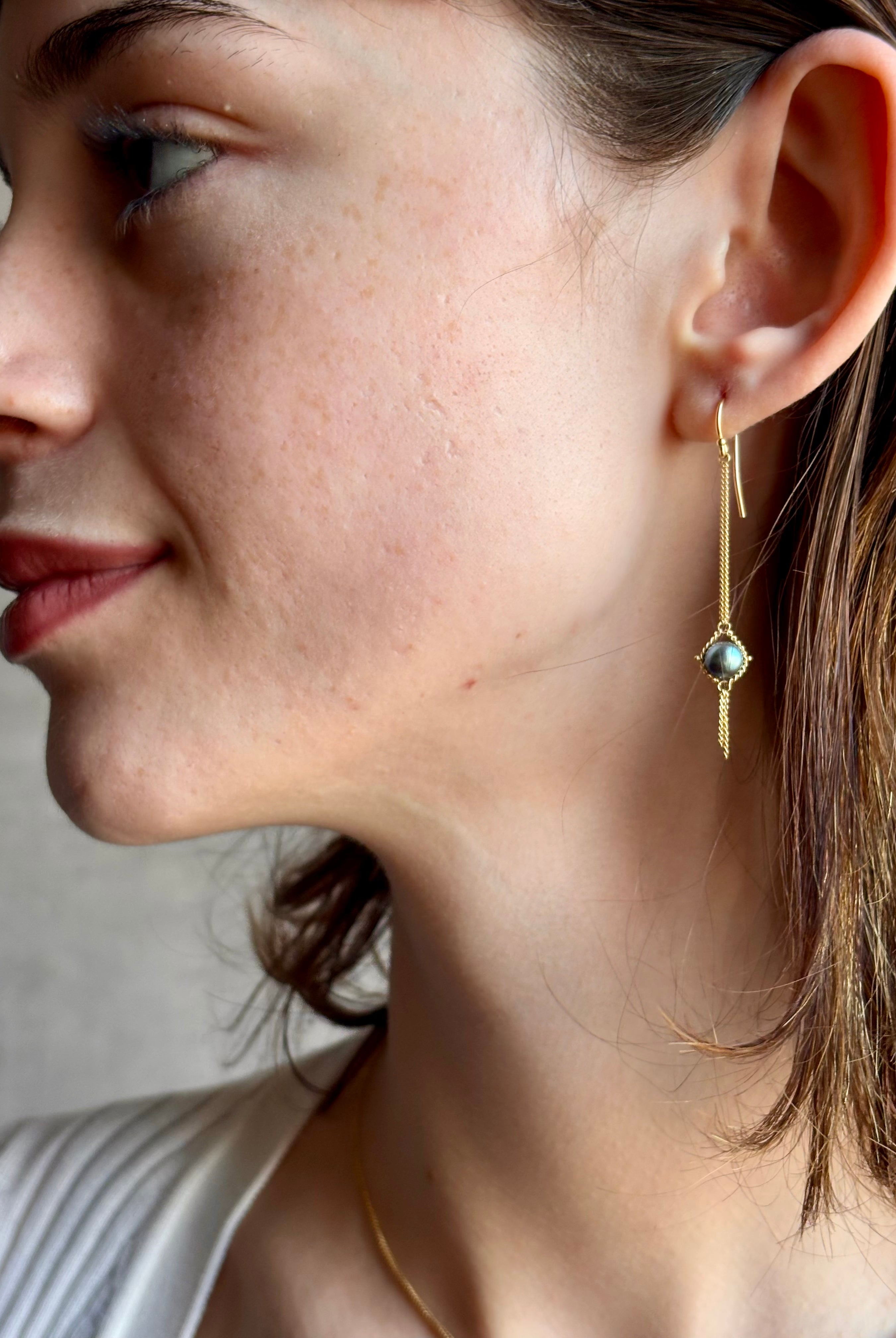 Woman wearing refined fine jewelry with iridescent blue Akoya pearls in an elegantly wearable drop silhouette in 18k yellow gold from New york designer Amali with kinetic fun fringe bottom detail