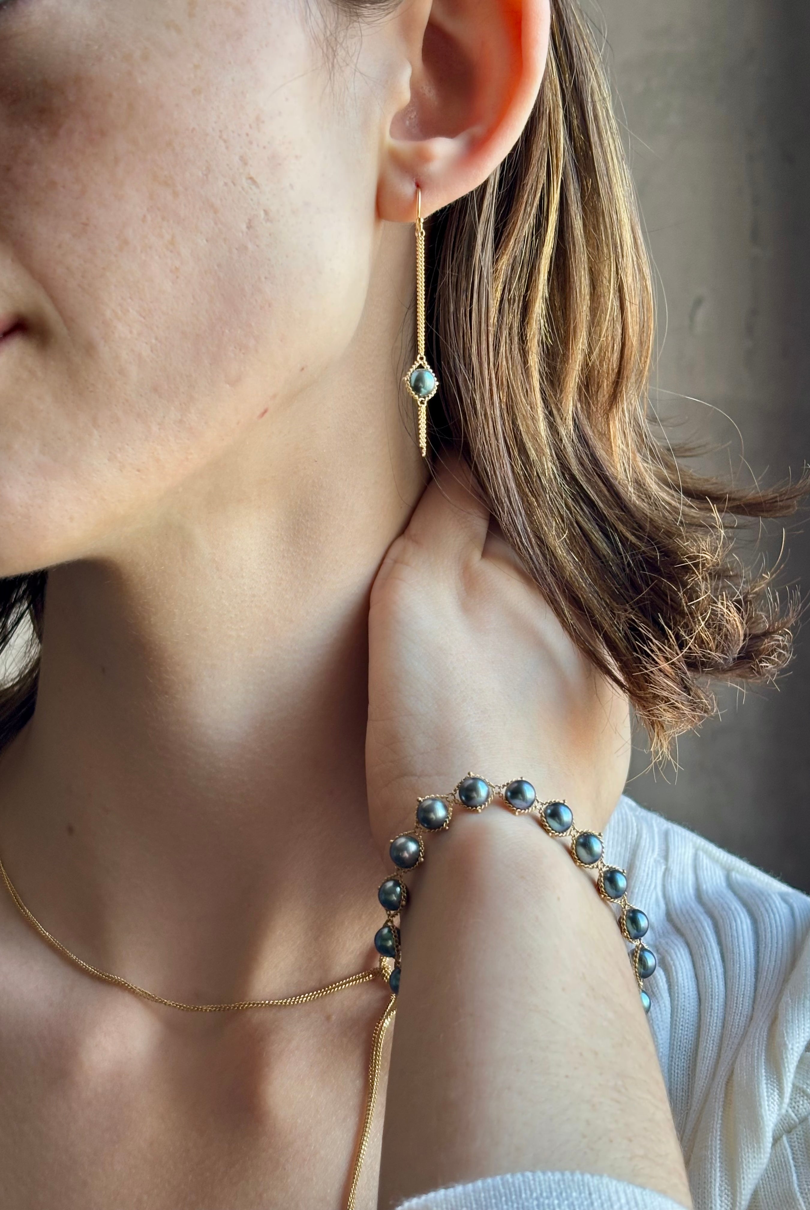 Woman wearing refined fine jewelry with iridescent blue Akoya pearls in an elegantly wearable drop silhouette in 18k yellow gold from New york designer Amali with kinetic fun fringe bottom detail