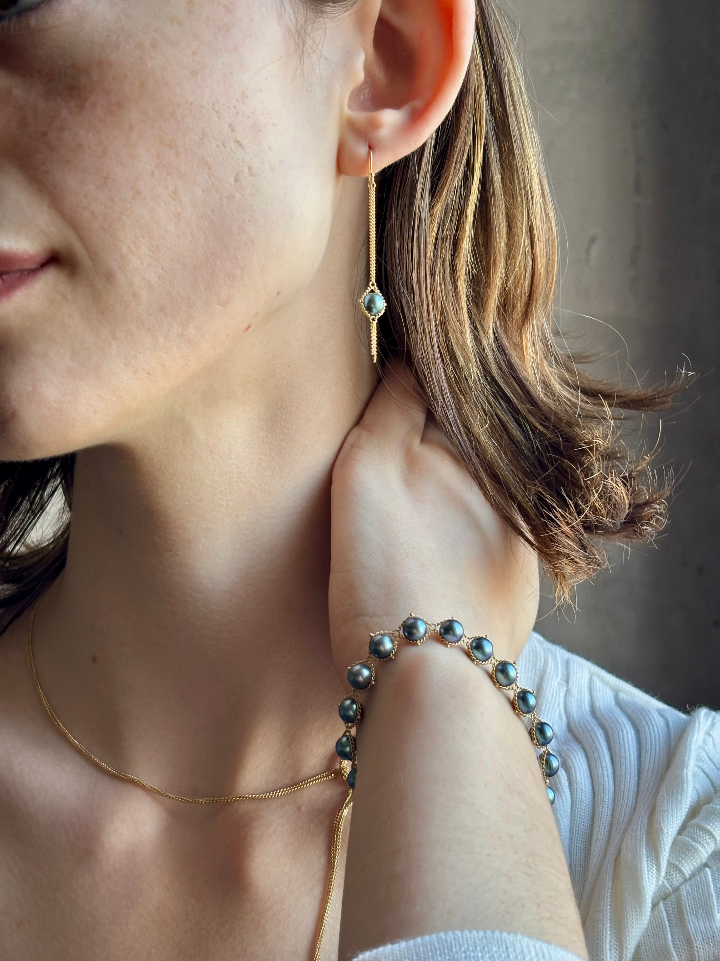 Woman wearing refined fine jewelry with iridescent blue Akoya pearls in an elegantly wearable drop silhouette in 18k yellow gold from New york designer Amali with kinetic fun fringe bottom detail