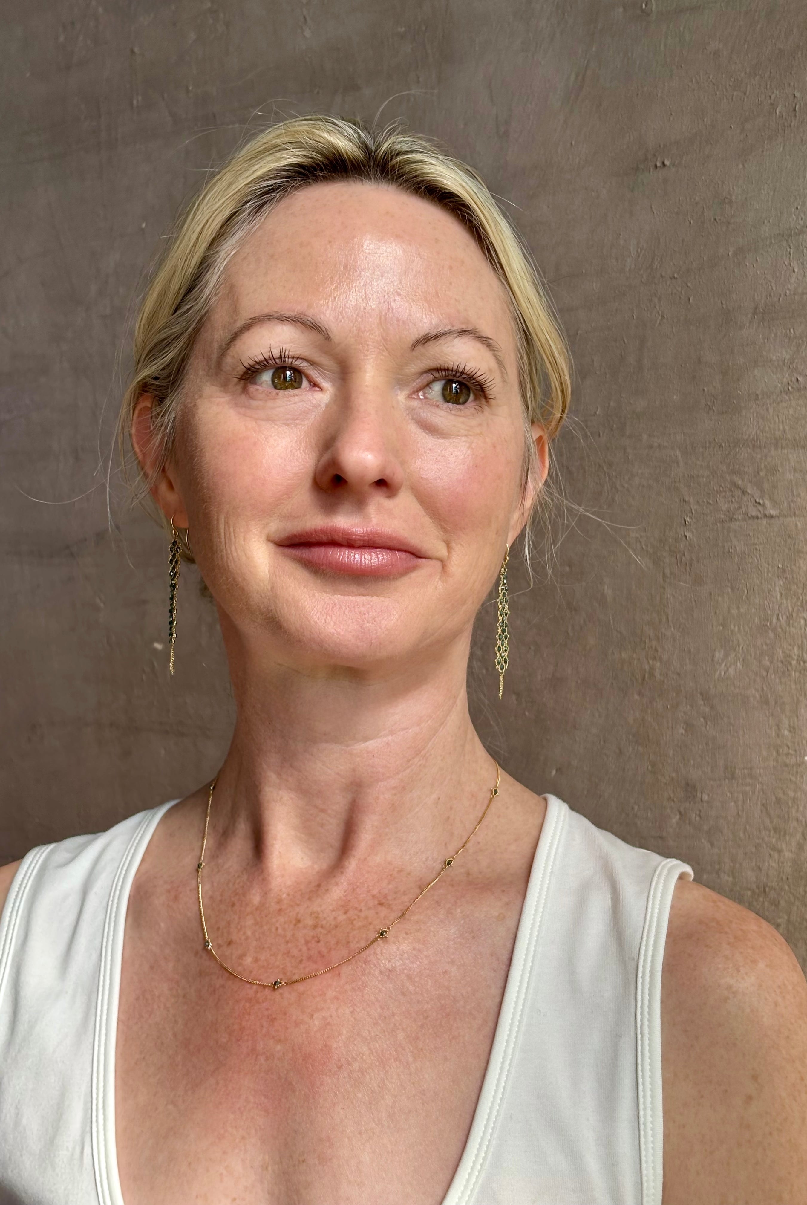 Mature woman wearing a natural blue diamond chain necklace handcrafted by North Carolina fine jewelry designer Amali in warm 18K yellow gold with a refreshing contemporary design