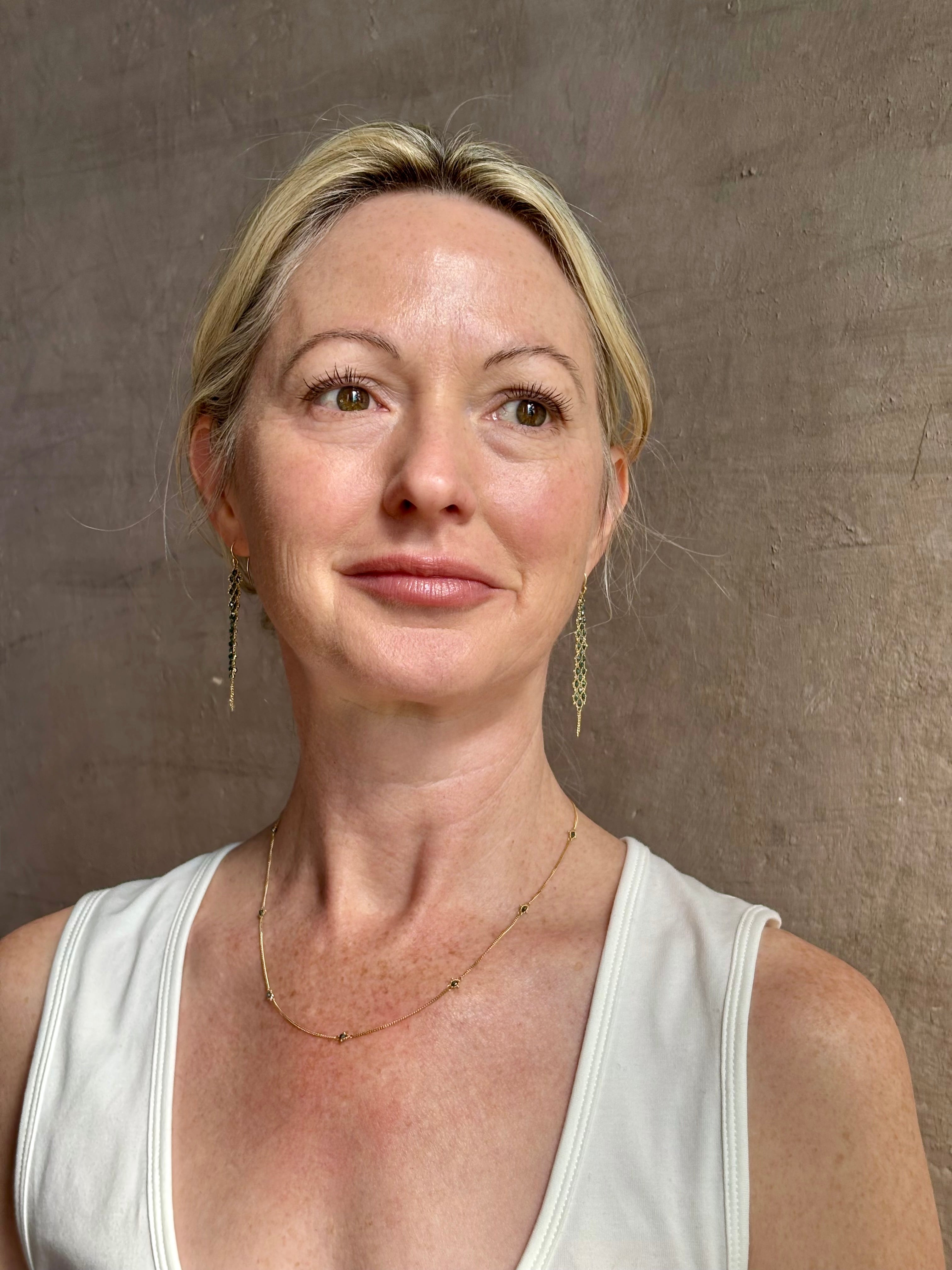 Mature woman wearing a natural blue diamond chain necklace handcrafted by North Carolina fine jewelry designer Amali in warm 18K yellow gold with a refreshing contemporary design