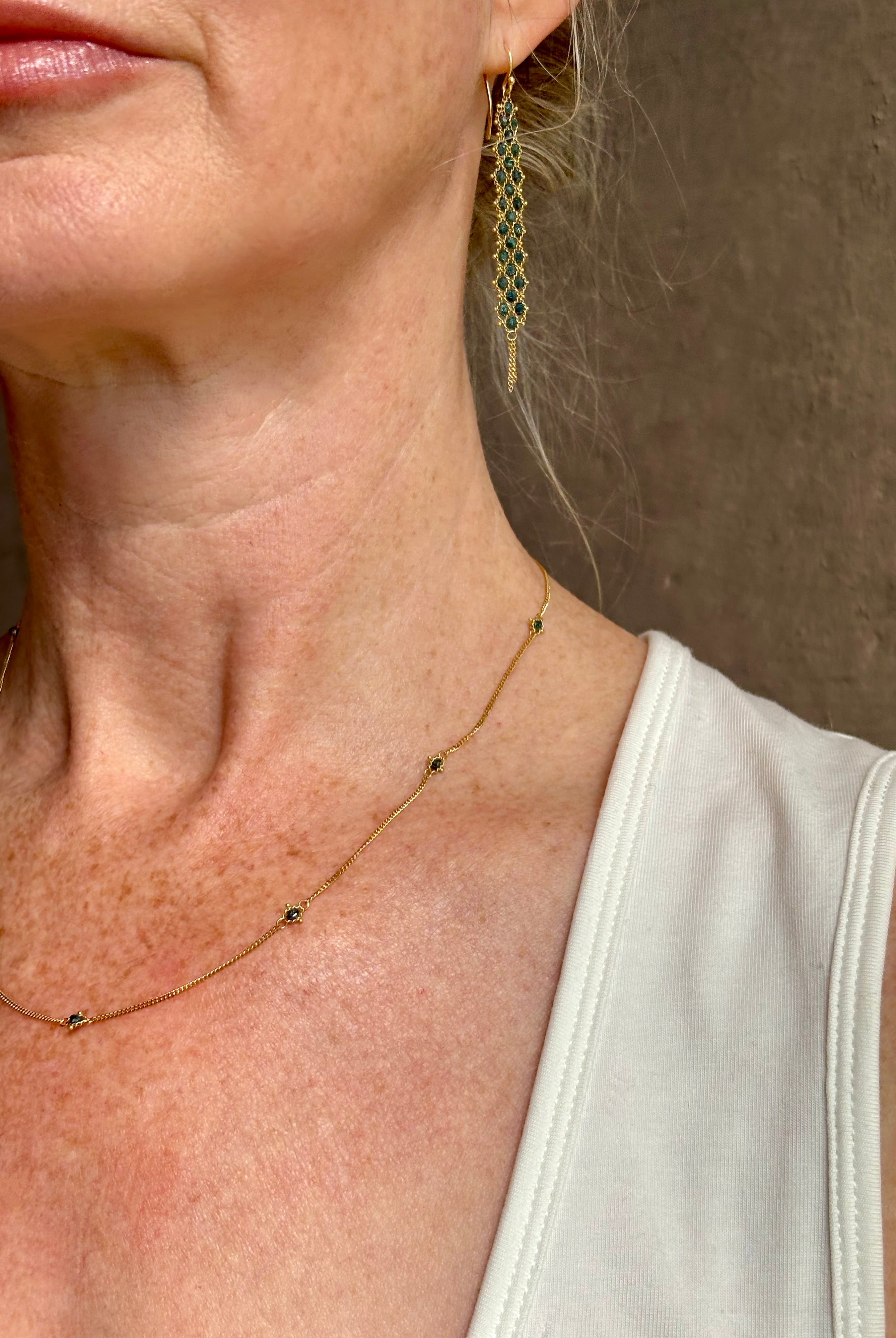 Mature woman wearing a natural blue diamond chain necklace handcrafted by North Carolina fine jewelry designer Amali in warm 18K yellow gold with a refreshing contemporary design