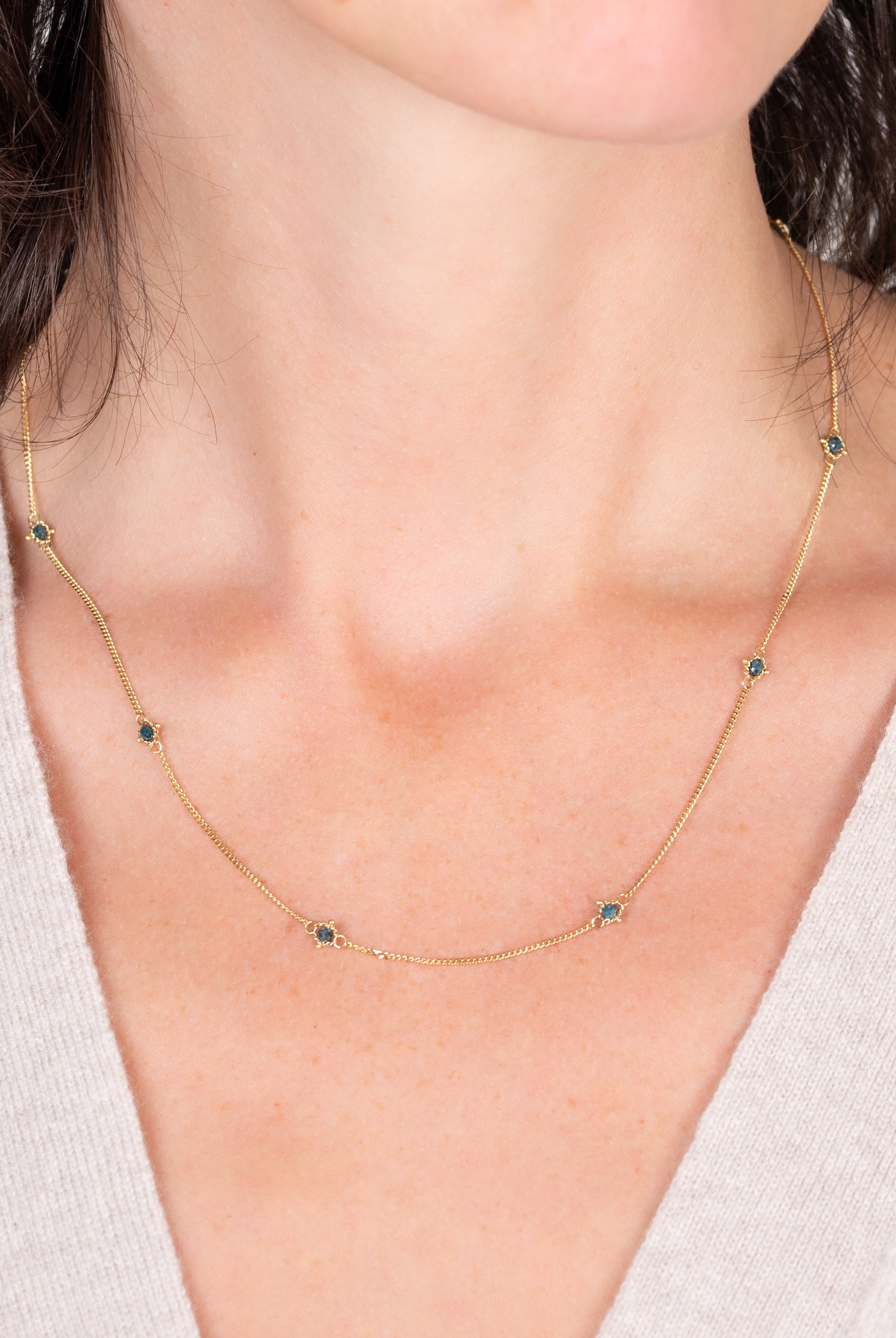 Image of a woman wearing a natural blue diamond chain necklace handcrafted by North Carolina fine jewelry designer Amali in warm 18K yellow gold with a refreshing contemporary design