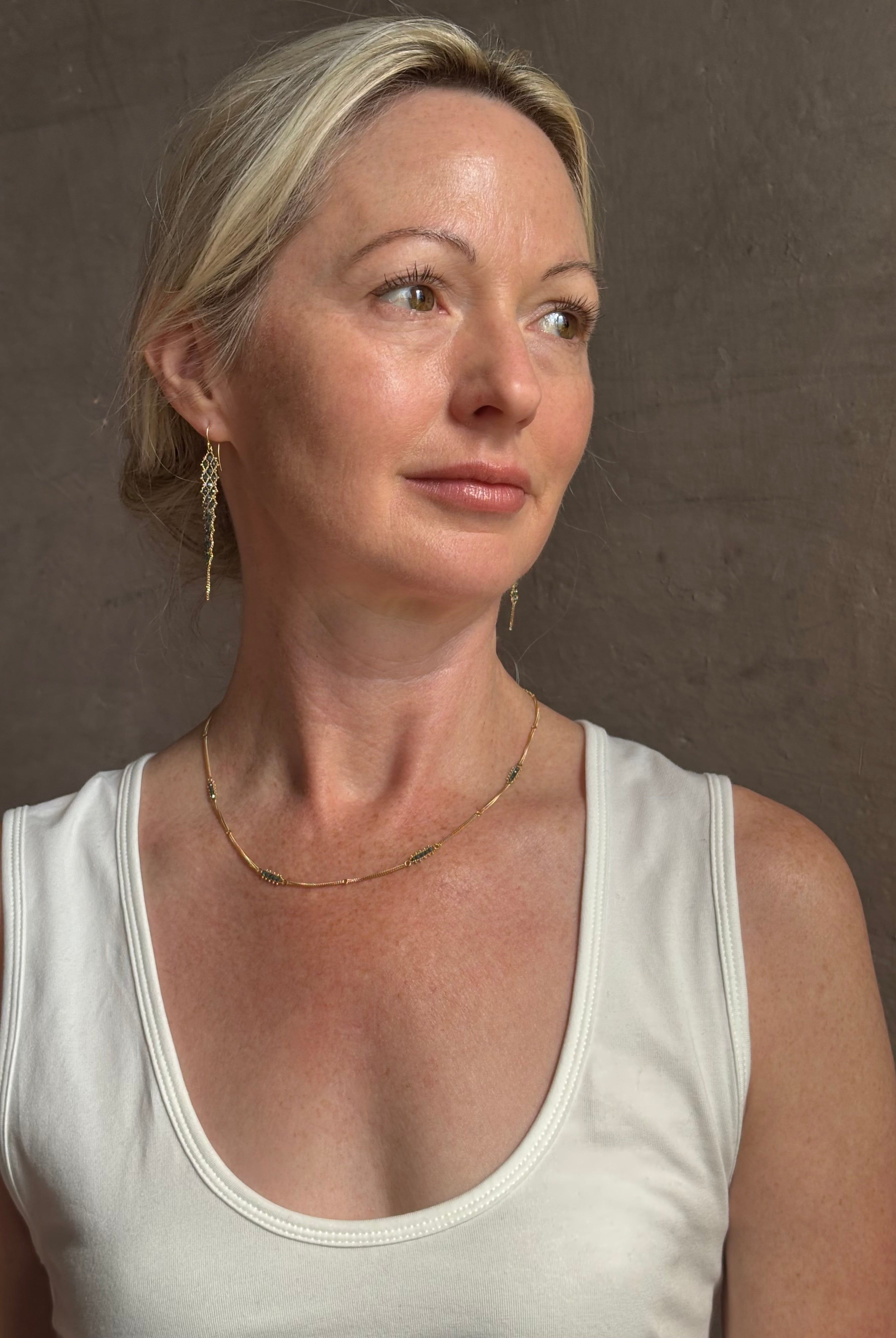 Mature woman wearing a double layered chain natural blue diamond necklace from fine jewelry designer Amali handcrafted in Chapel Hill North Carolina in warm 18K yellow gold