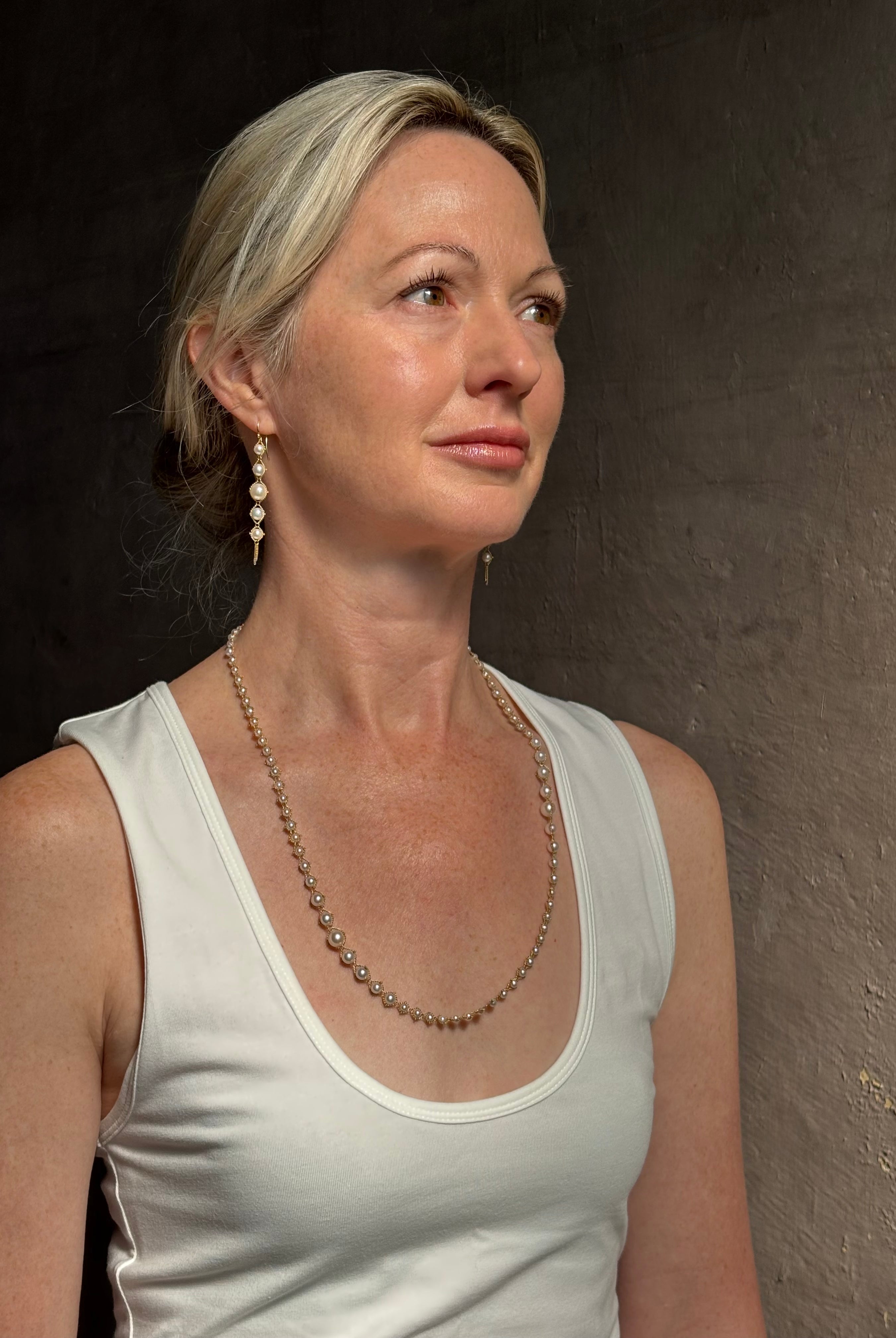 Image of graduated Akoya Pearl Drop Earrings from North Carolina fine jewelry artist Amali with each lustrous white Akoya pearl individually suspended in hand-woven lengths of delicate 18K yellow gold chain and french wire hooks