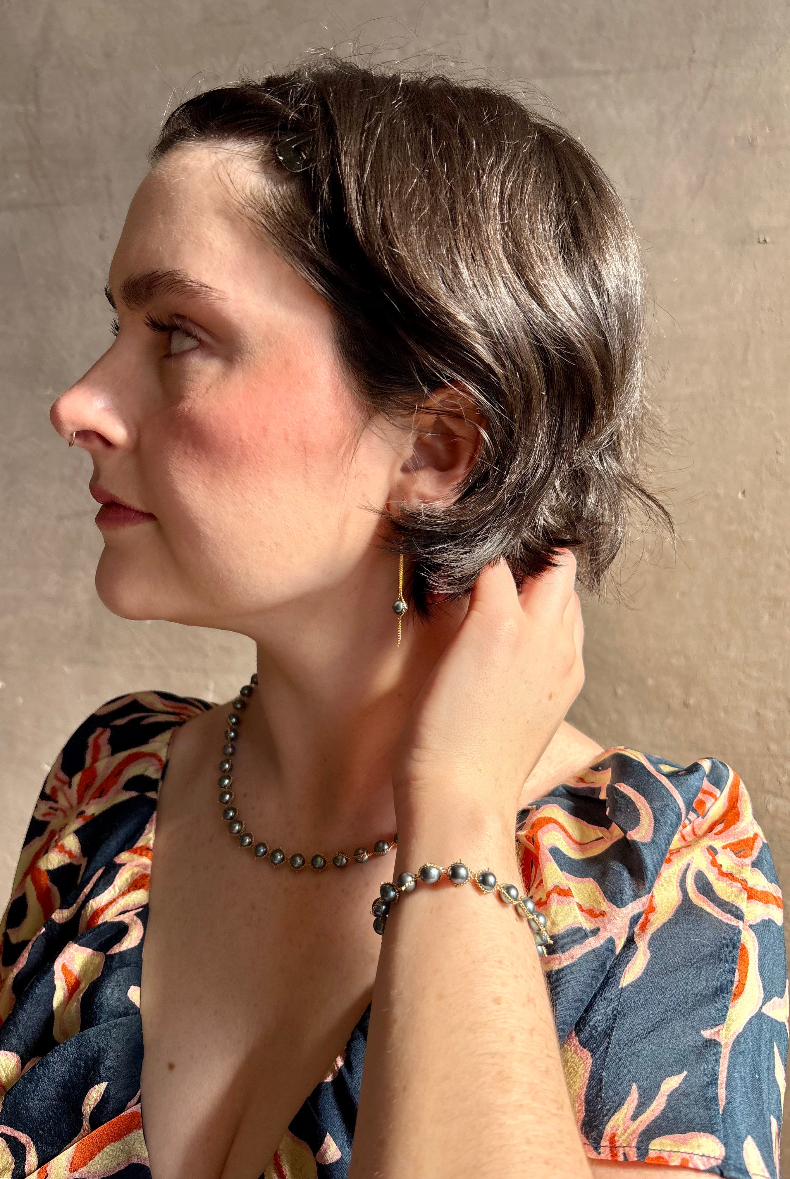 Woman wearing luxury Grey Akoya Pearl Necklace from fine jewelry artist Amali handcrafted in New York in warm 18K yellow gold with matching necklace and earrings