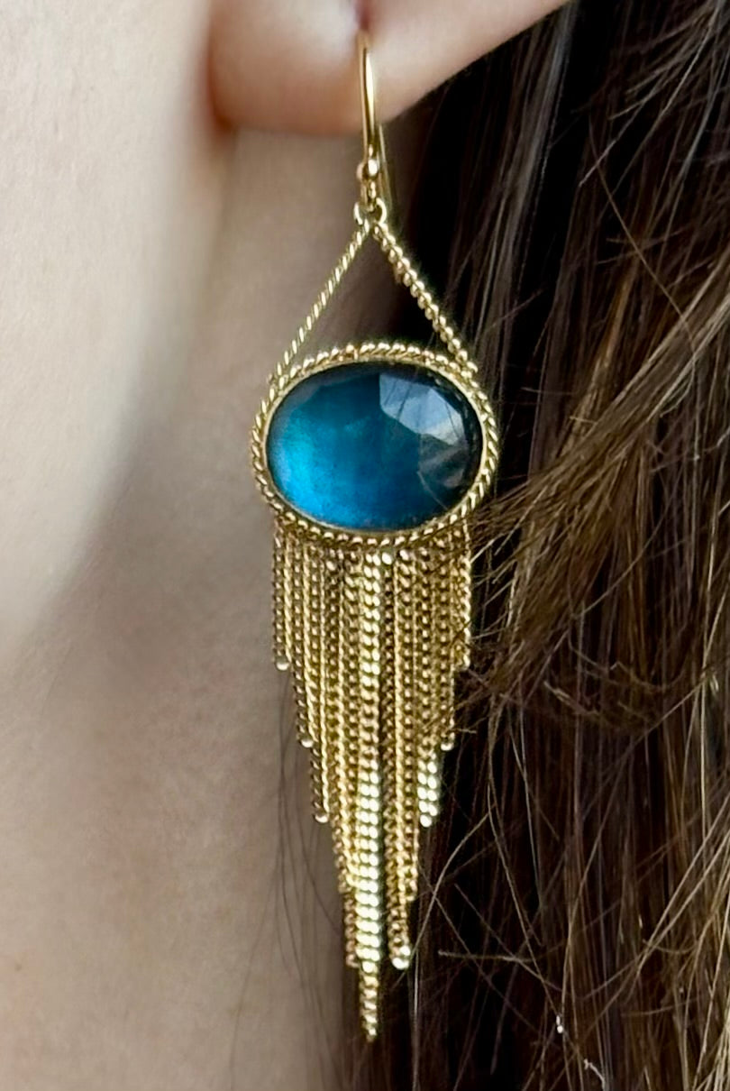 Woman wearing the London Blue Topaz statement drop Earrings from Amali are handcrafted in New York with 18K yellow gold with kinetic gold fringe detail finish at bottom