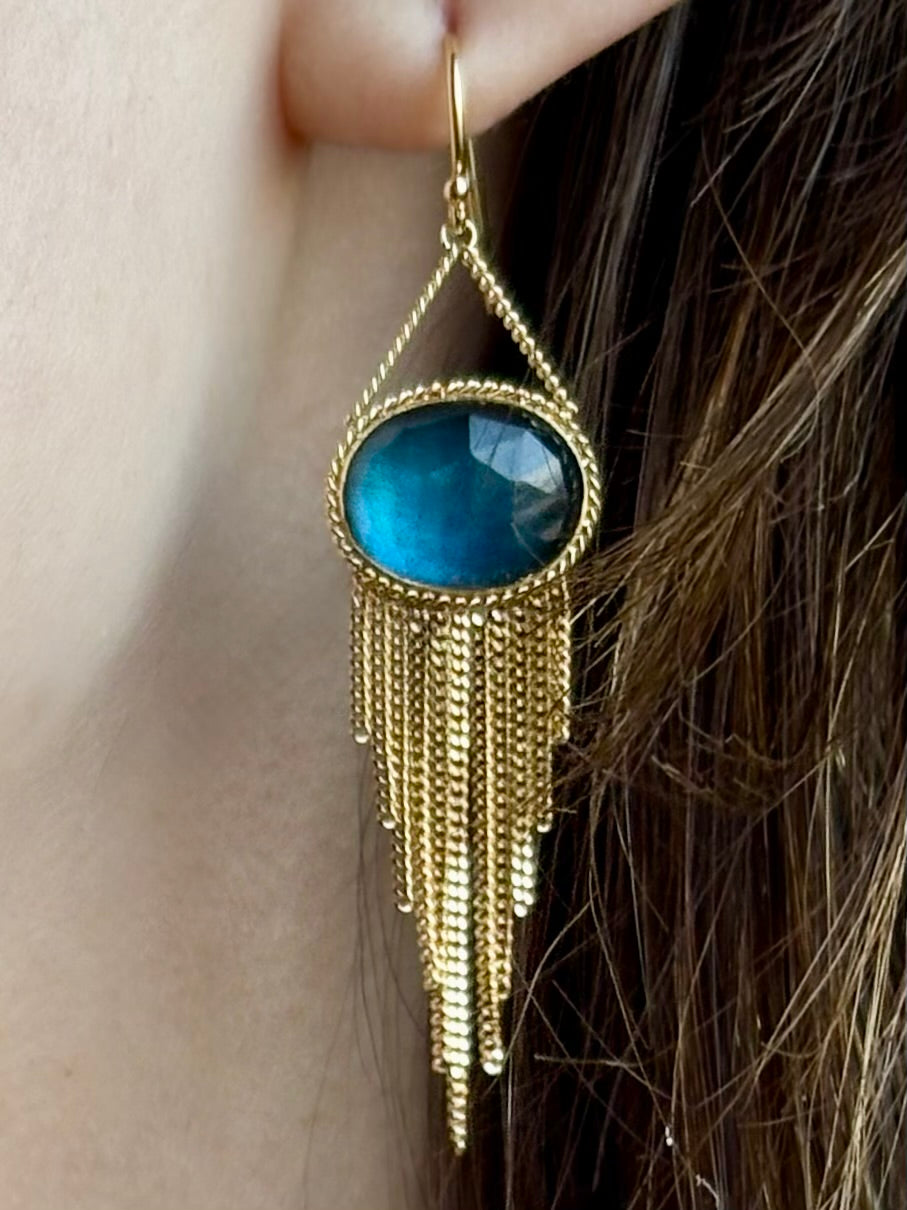 Woman wearing the London Blue Topaz statement drop Earrings from Amali are handcrafted in New York with 18K yellow gold with kinetic gold fringe detail finish at bottom