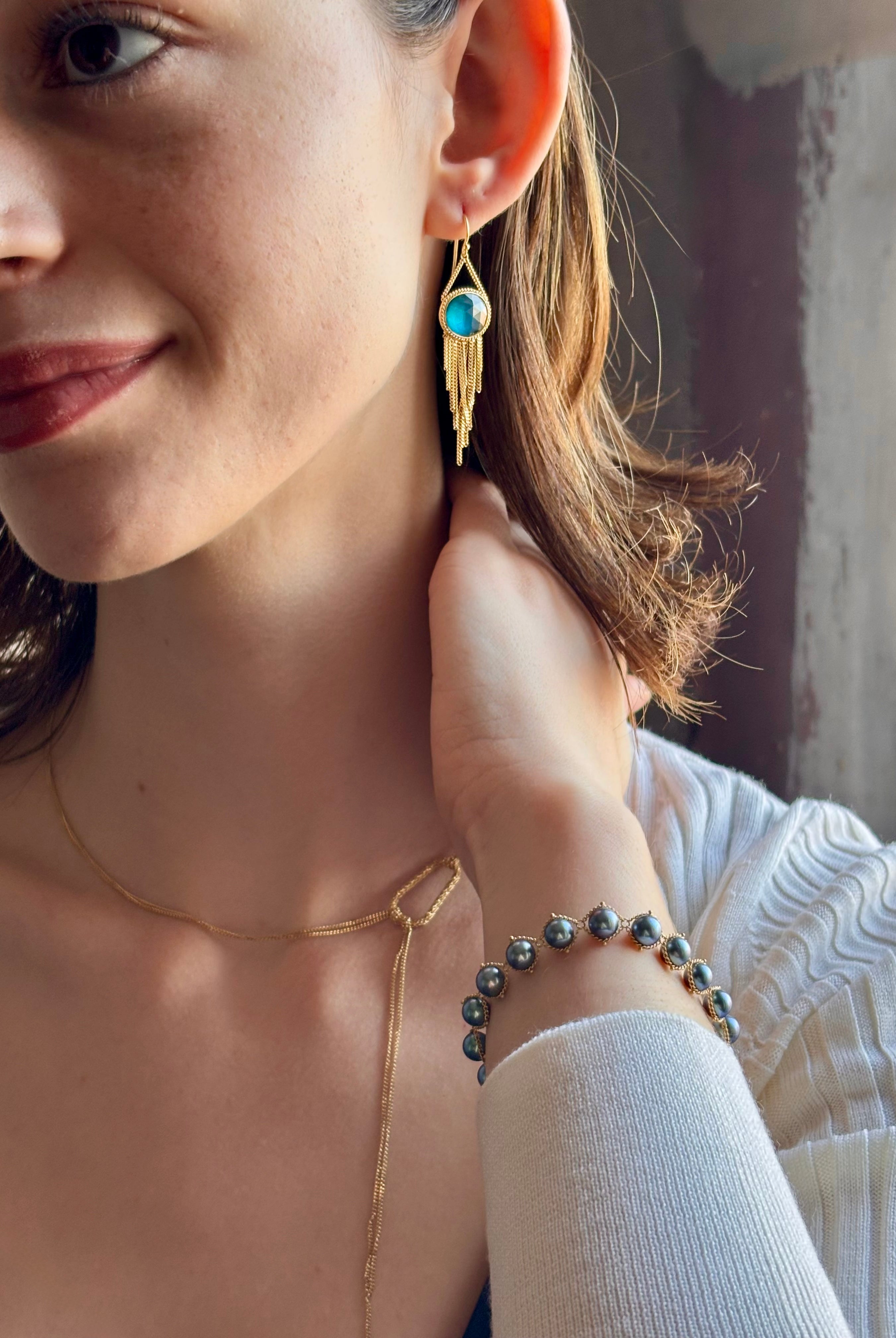 Woman wearing the London Blue Topaz statement drop Earrings from Amali are handcrafted in New York with 18K yellow gold with kinetic gold fringe detail finish at bottom
