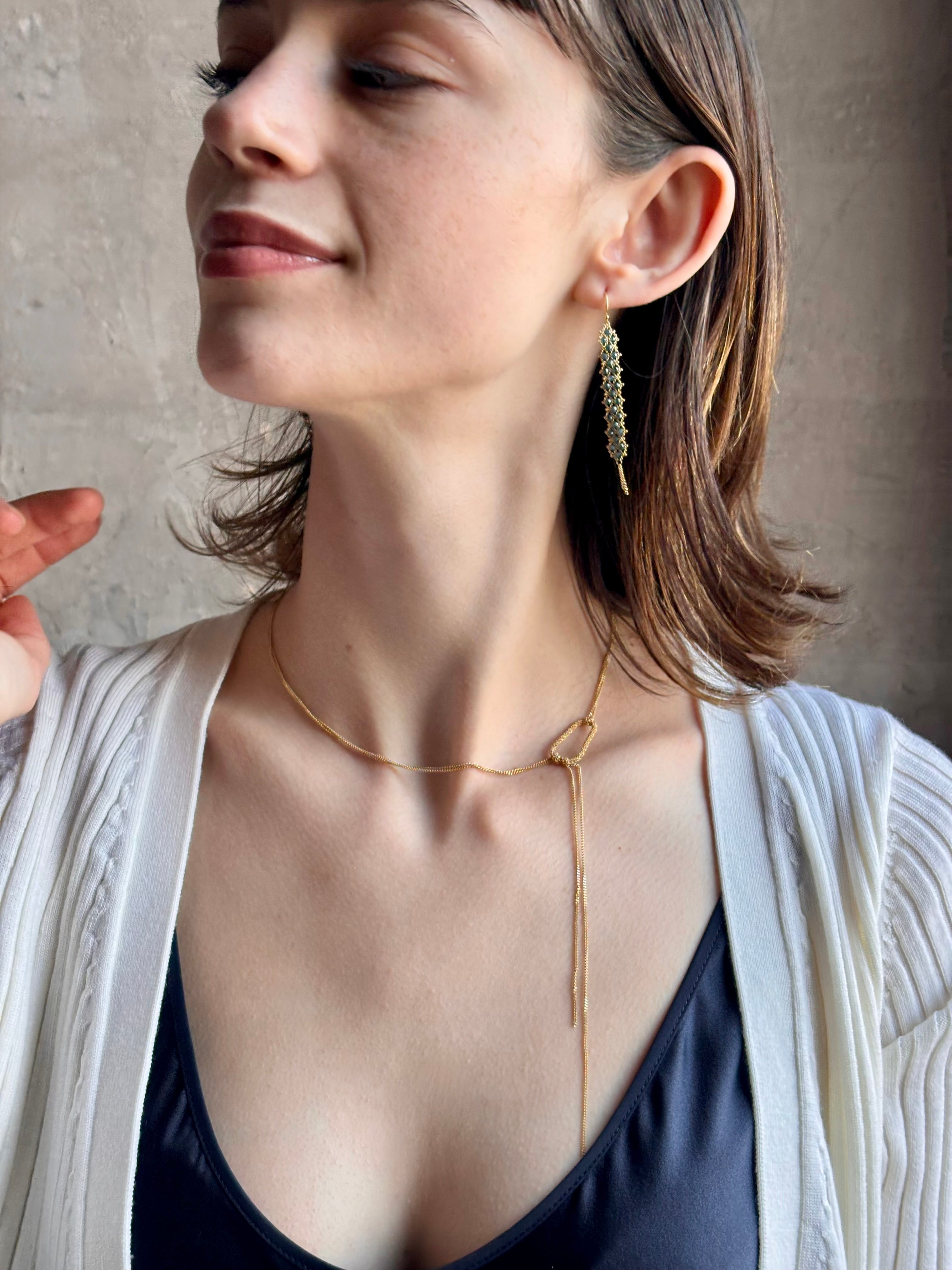 Woman wearing hand woven blue diamonds and 18k yellow gold earrings by New York jewelry designer Amali