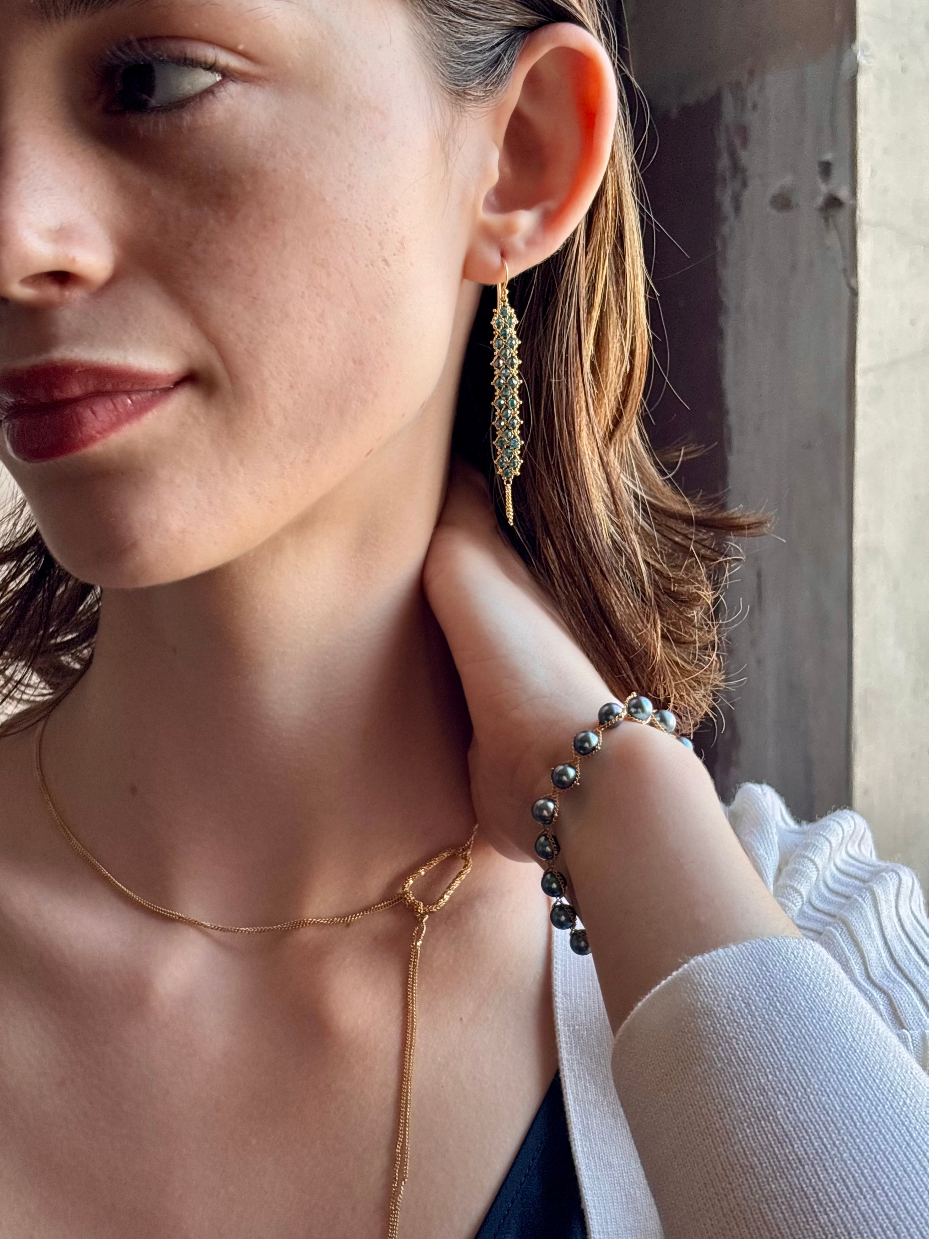 Woman wearing hand woven blue diamonds and 18k yellow gold earrings by New York jewelry designer Amali