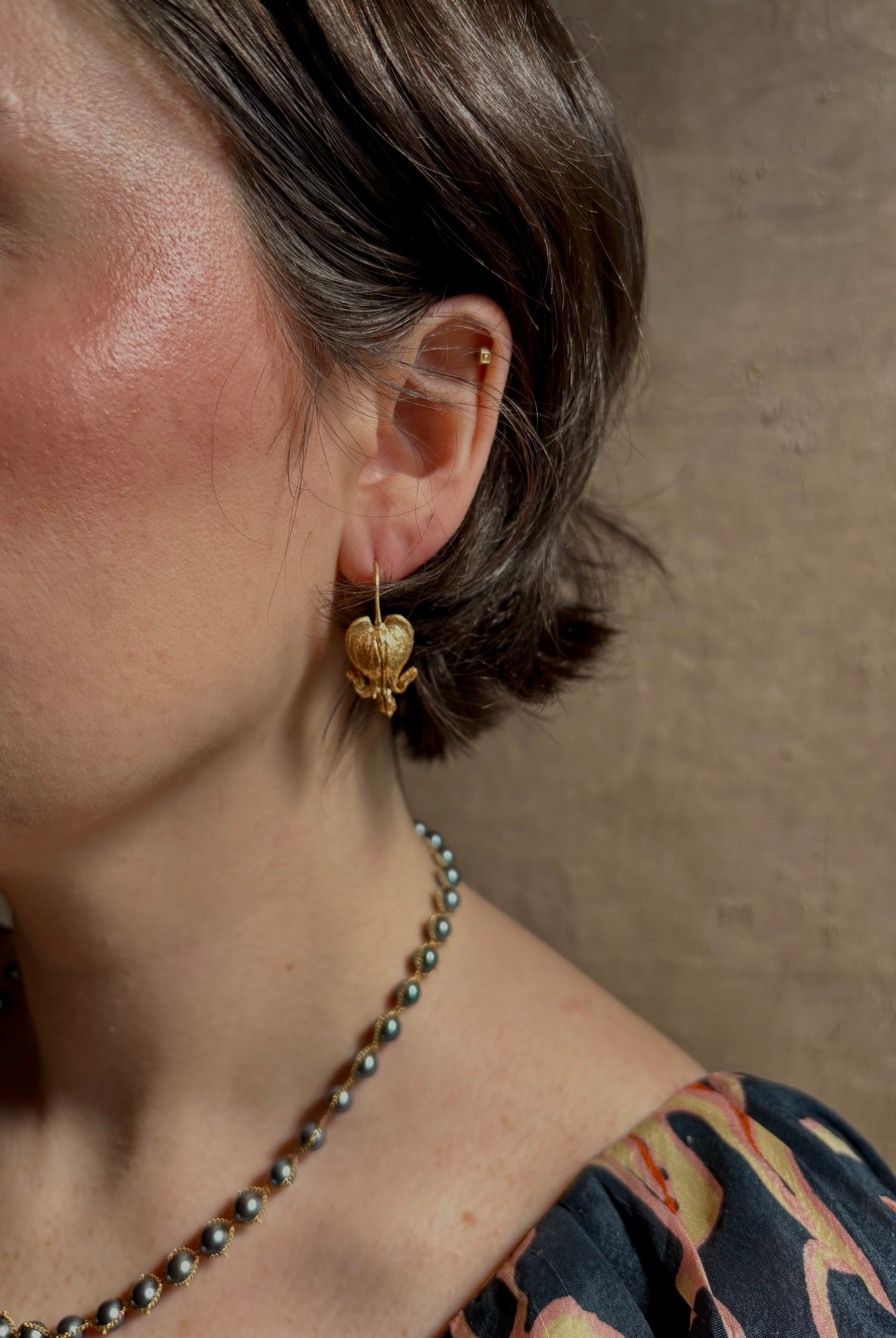 Woman wearing Bleeding Heart Hoop Earrings from North Carolina fine Jewelry artist Amber Mahler handcrafted 18K yellow gold vermeil botanical casting.