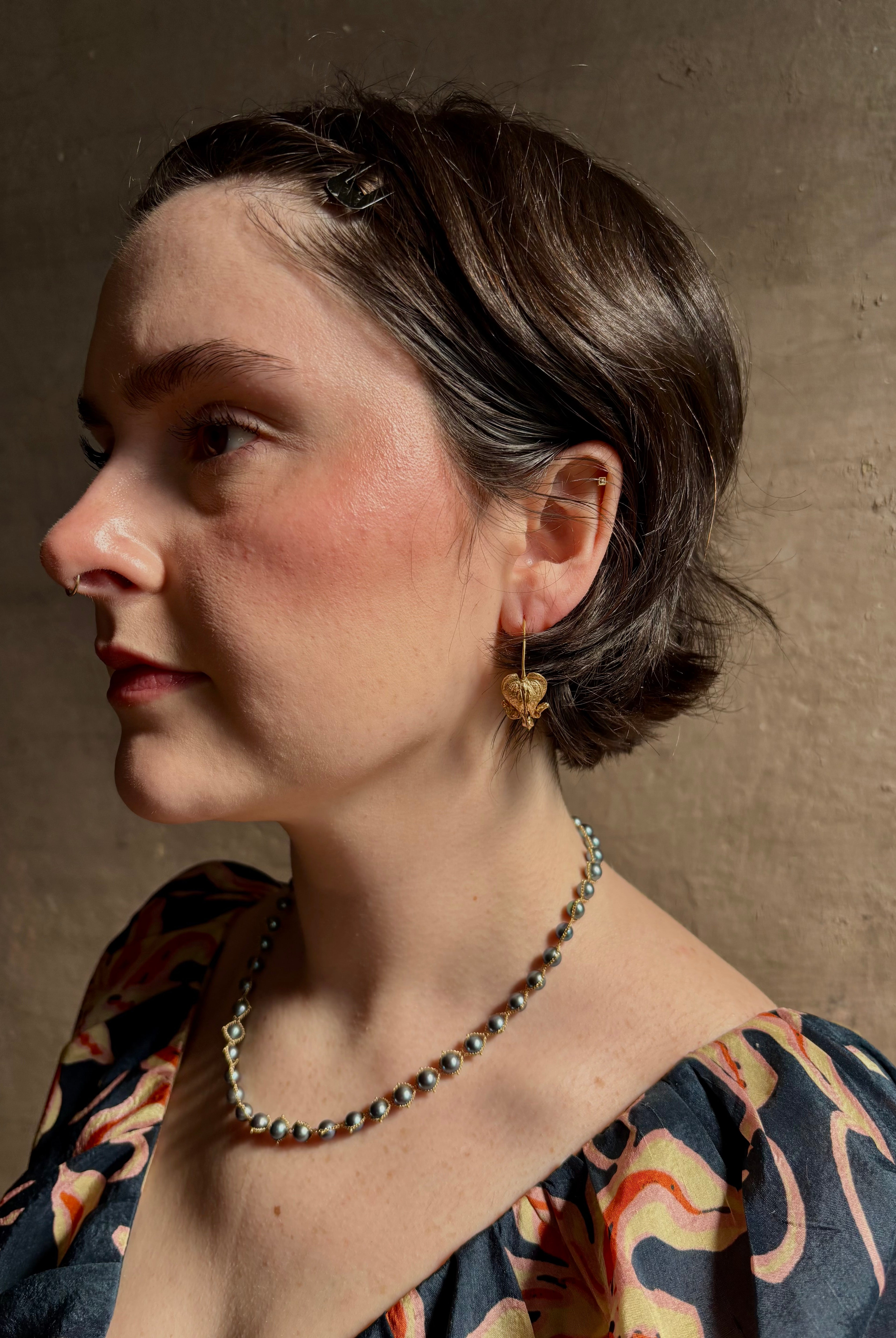 Woman wearing Bleeding Heart Hoop Earrings from North Carolina fine Jewelry artist Amber Mahler handcrafted 18K yellow gold vermeil botanical casting.