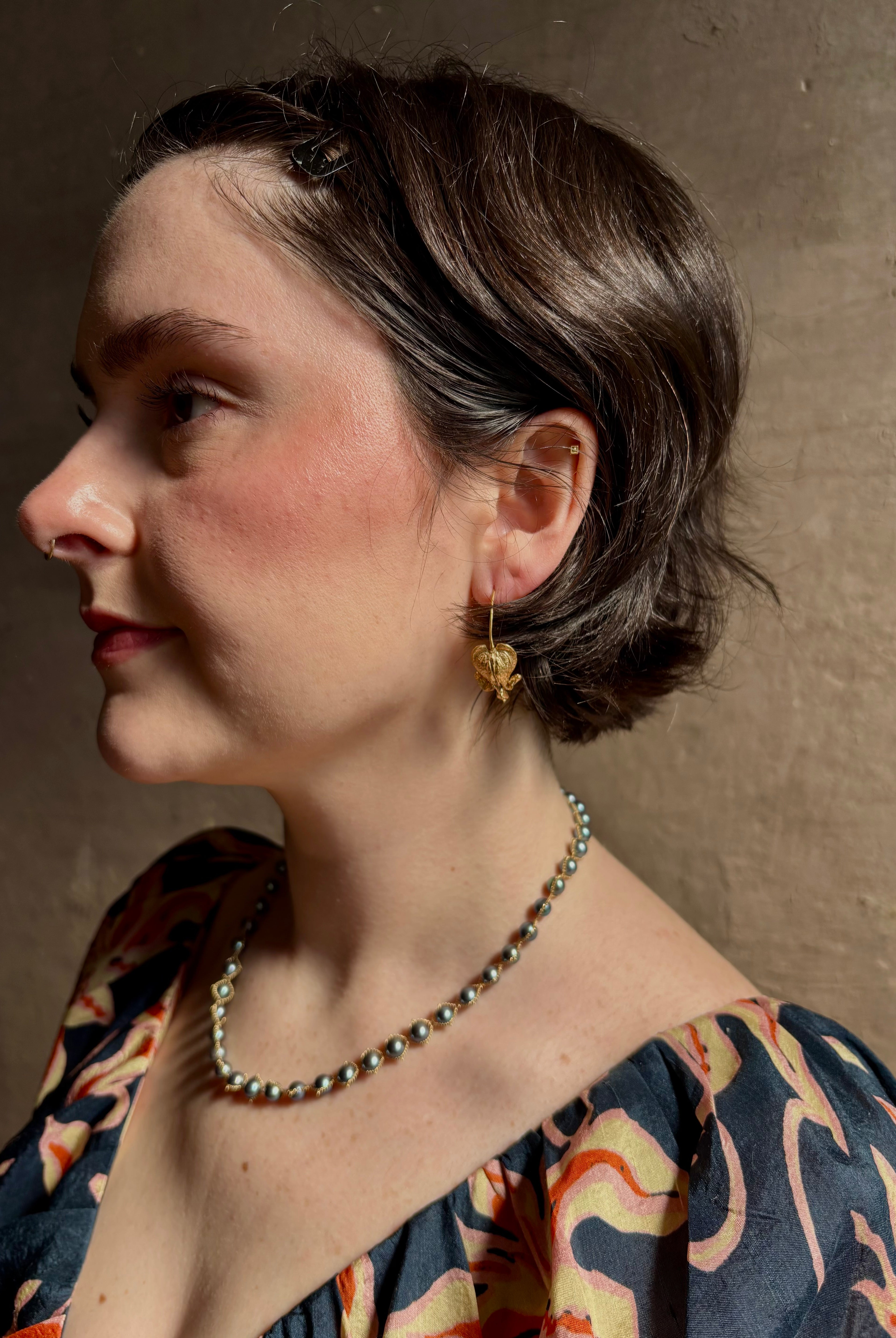 Woman wearing Bleeding Heart Hoop Earrings from North Carolina fine Jewelry artist Amber Mahler handcrafted 18K yellow gold vermeil botanical casting.