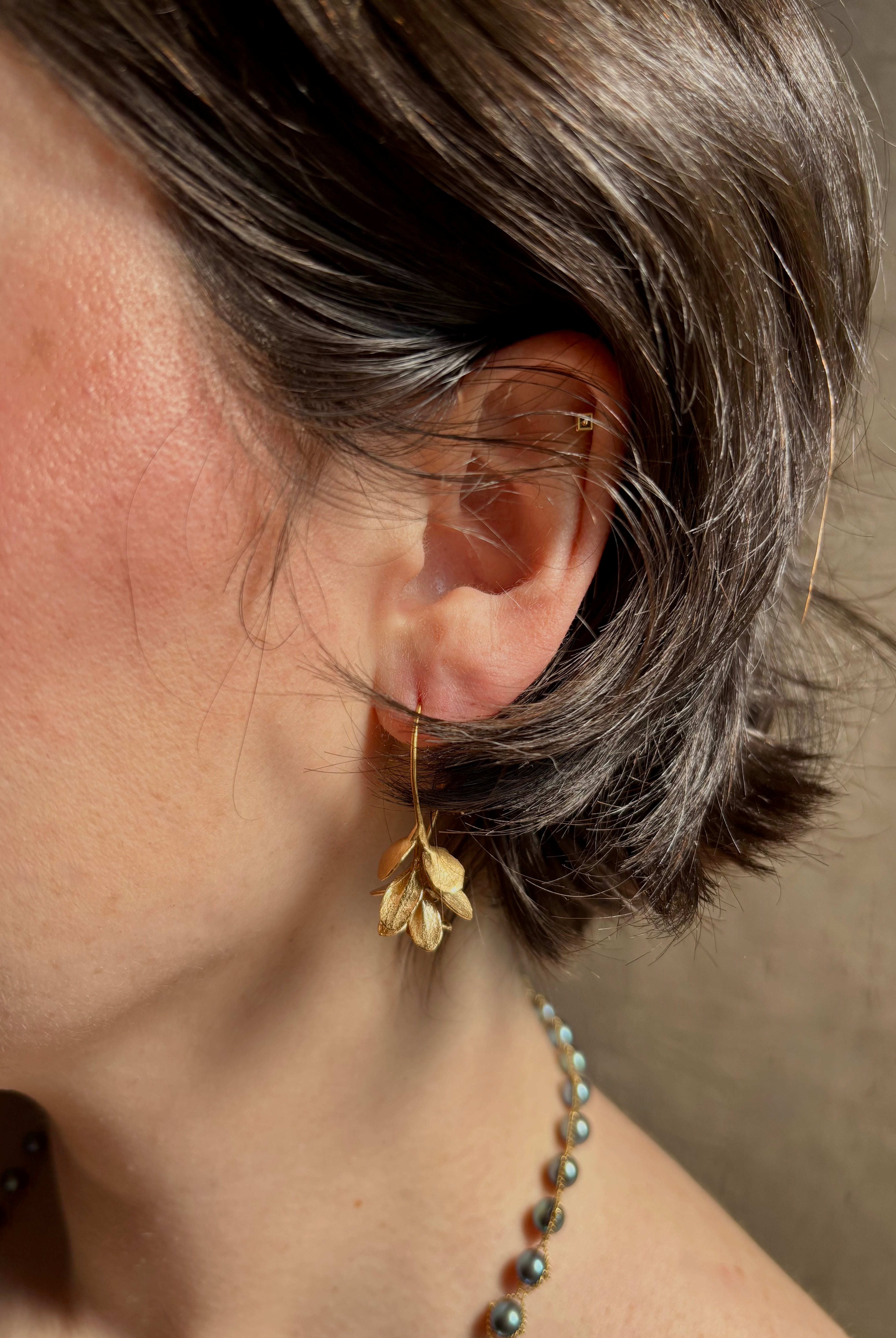 Woman wearing Four Petal Succulent Hoop Earrings from North Carolina fine jewelry artist Amber Mahler handcrafted 18K yellow gold vermeil botanical casting