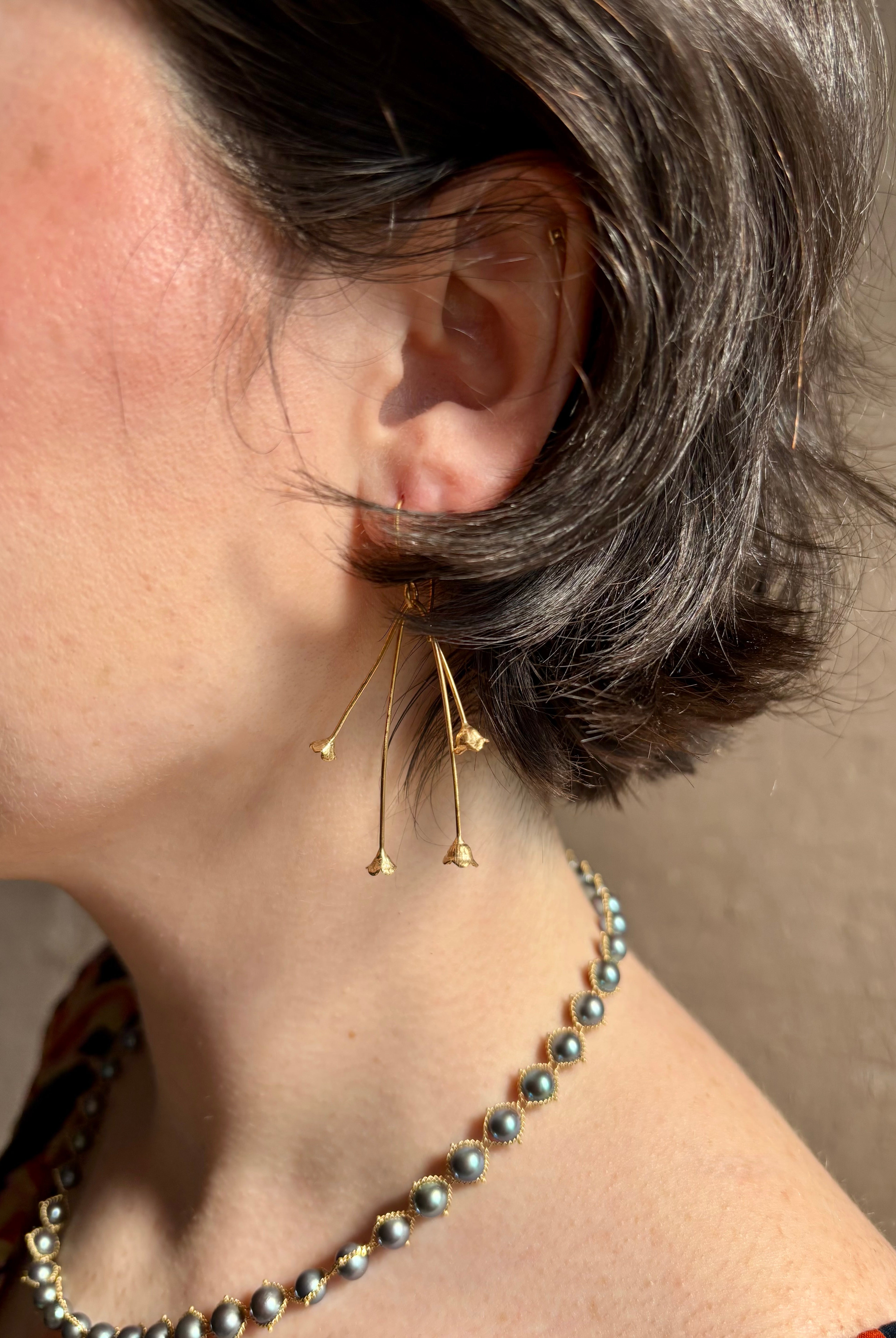 Woman wearing Lily of the Valley Earrings from North Carolna fine jewelry artist Amber Mahler handcrafted 18K yellow gold vermeil with four dangling flower blossoms