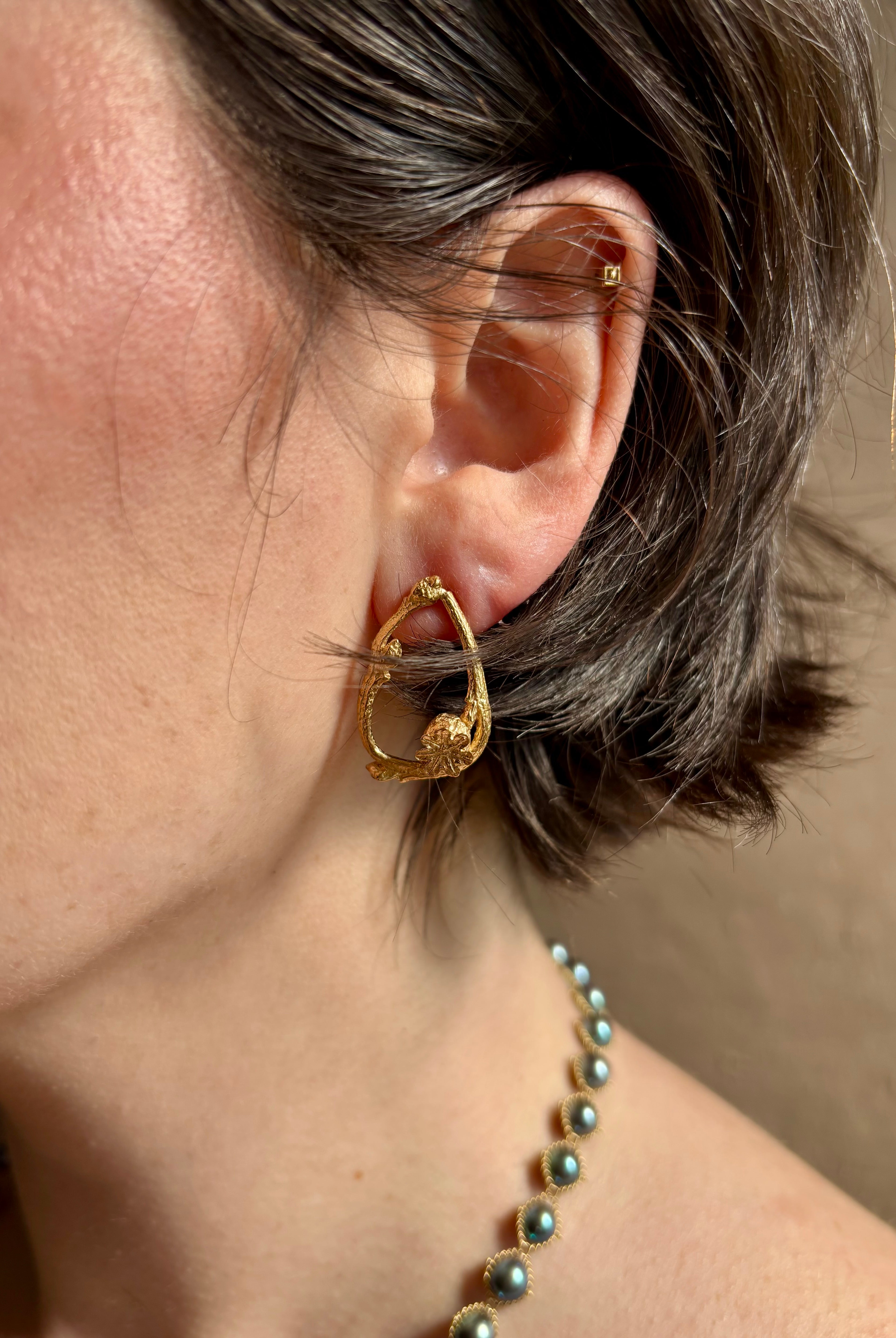 Woman wearing Poppy Pod and Blueberry Branch post Earrings from North Carolina fine jewelry artist Amber Mahler handcrafted 18K yellow gold vermeil casting.
