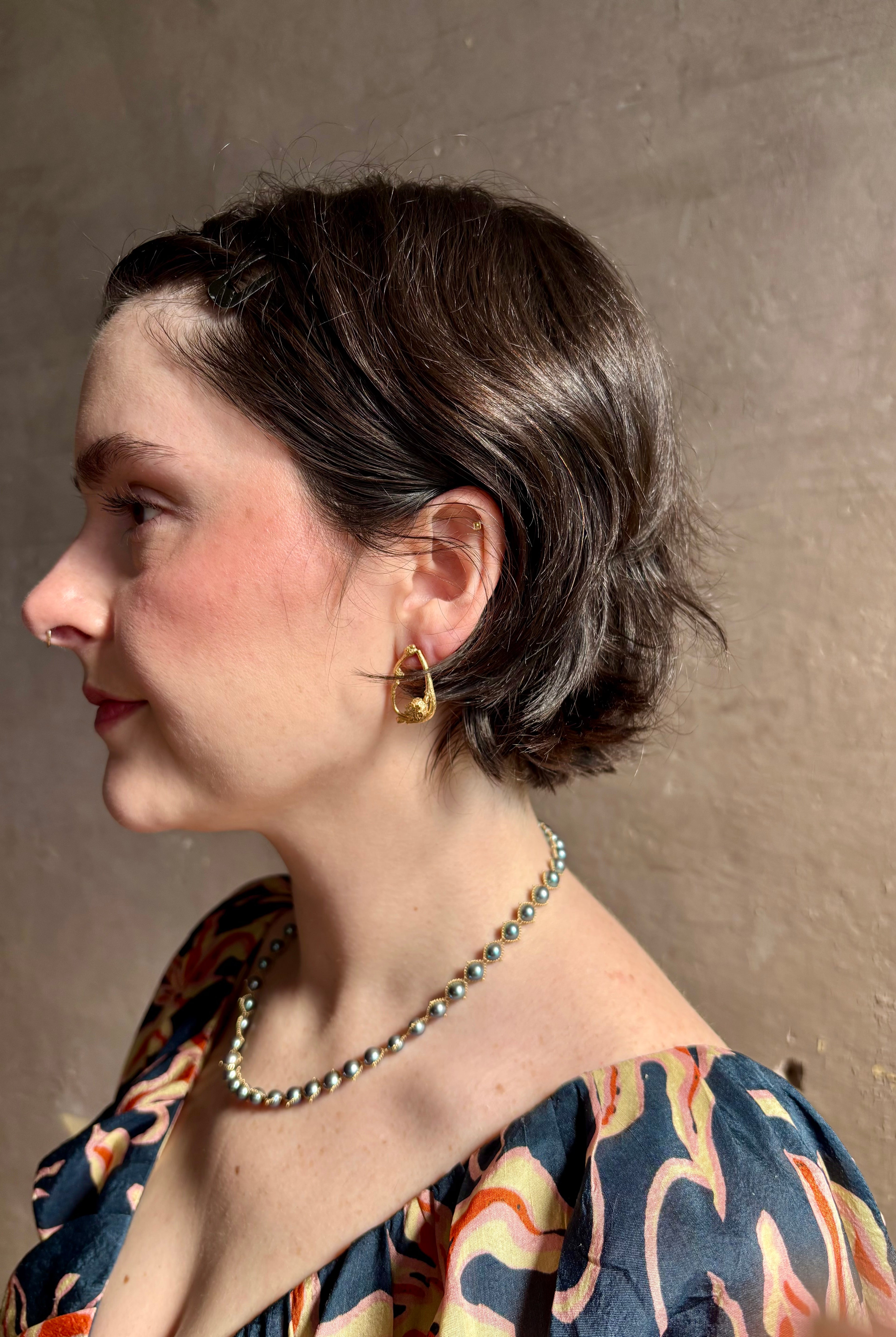 Woman wearing Poppy Pod and Blueberry Branch post Earrings from North Carolina fine jewelry artist Amber Mahler handcrafted 18K yellow gold vermeil casting.