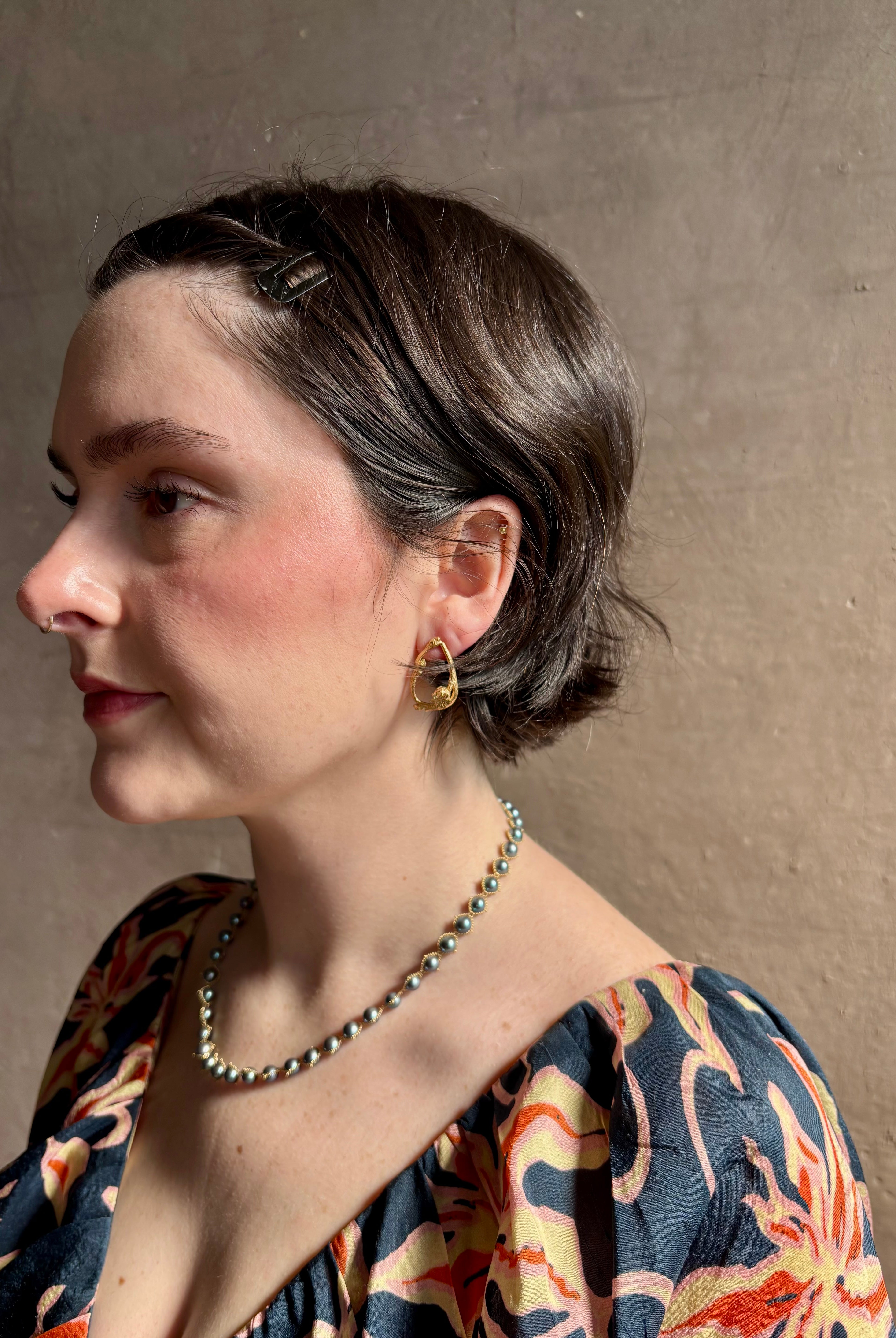 Woman wearing Poppy Pod and Blueberry Branch post Earrings from North Carolina fine jewelry artist Amber Mahler handcrafted 18K yellow gold vermeil casting.