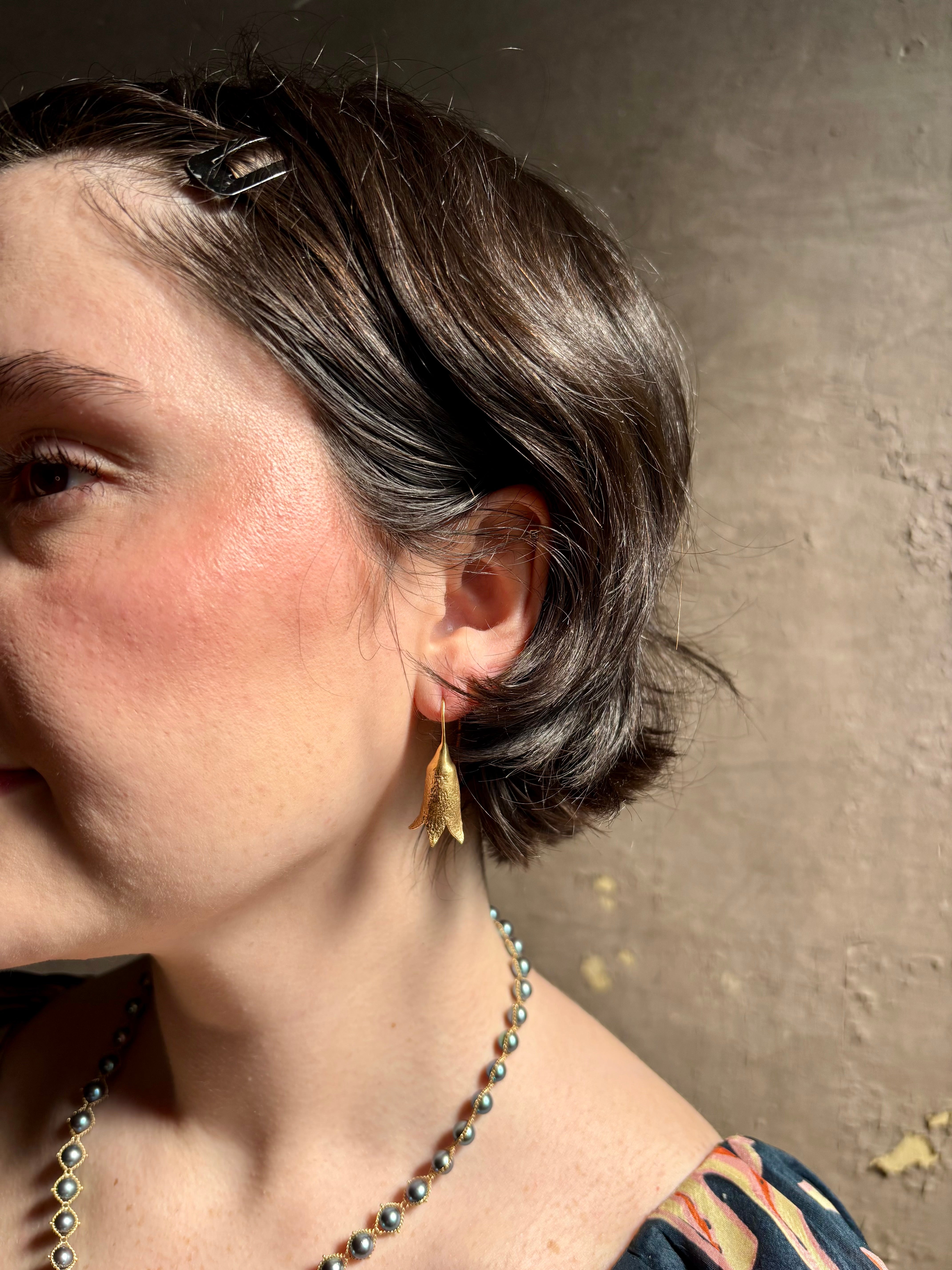 Woman wearing Silver Bells Hoop Earrings from North Carolina fine jewelry artist Amber Mahler in an exquisitely handcrafted 18K yellow gold vermeil botanical casting