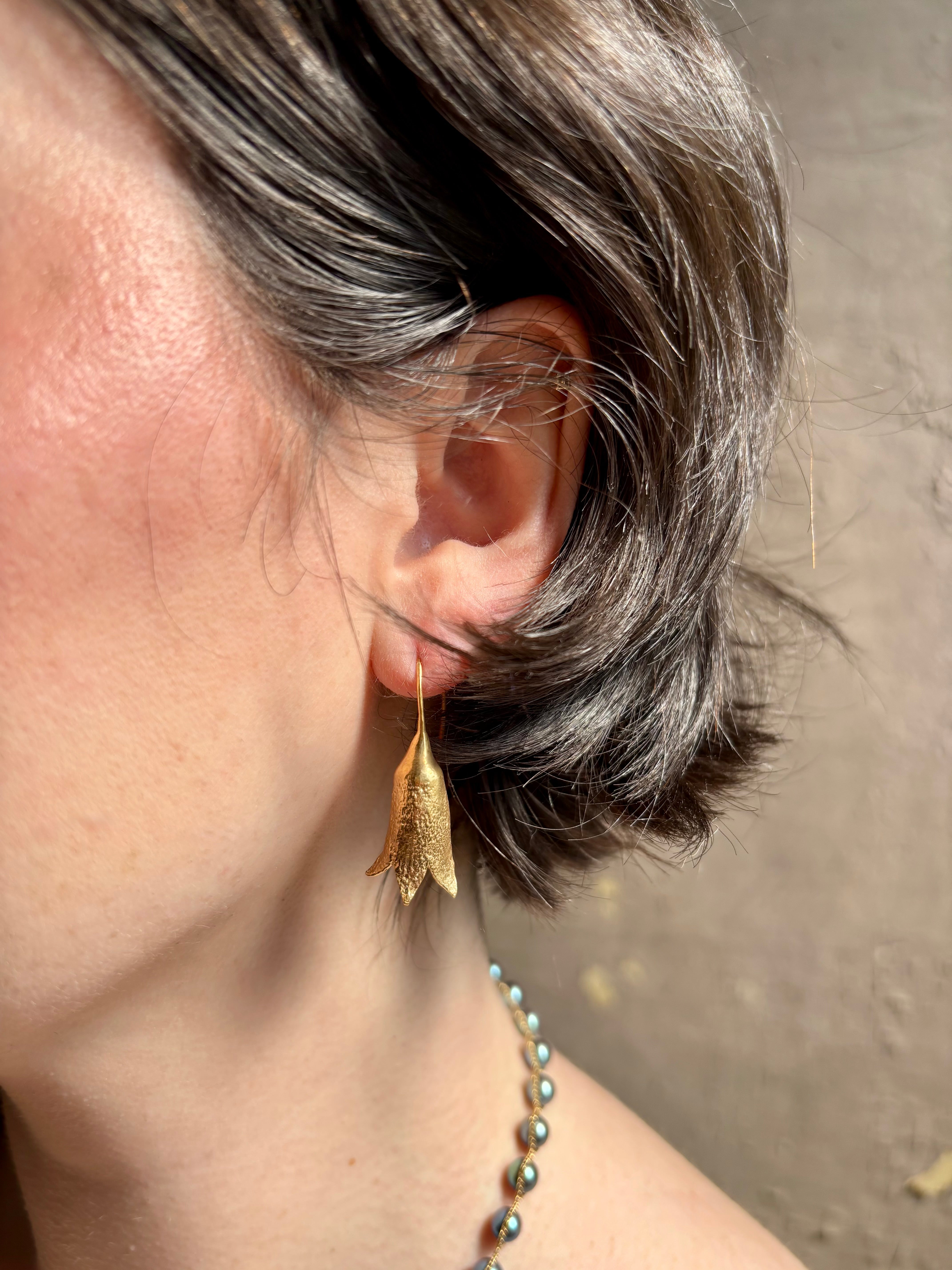 Woman wearing Silver Bells Hoop Earrings from North Carolina fine jewelry artist Amber Mahler in an exquisitely handcrafted 18K yellow gold vermeil botanical casting