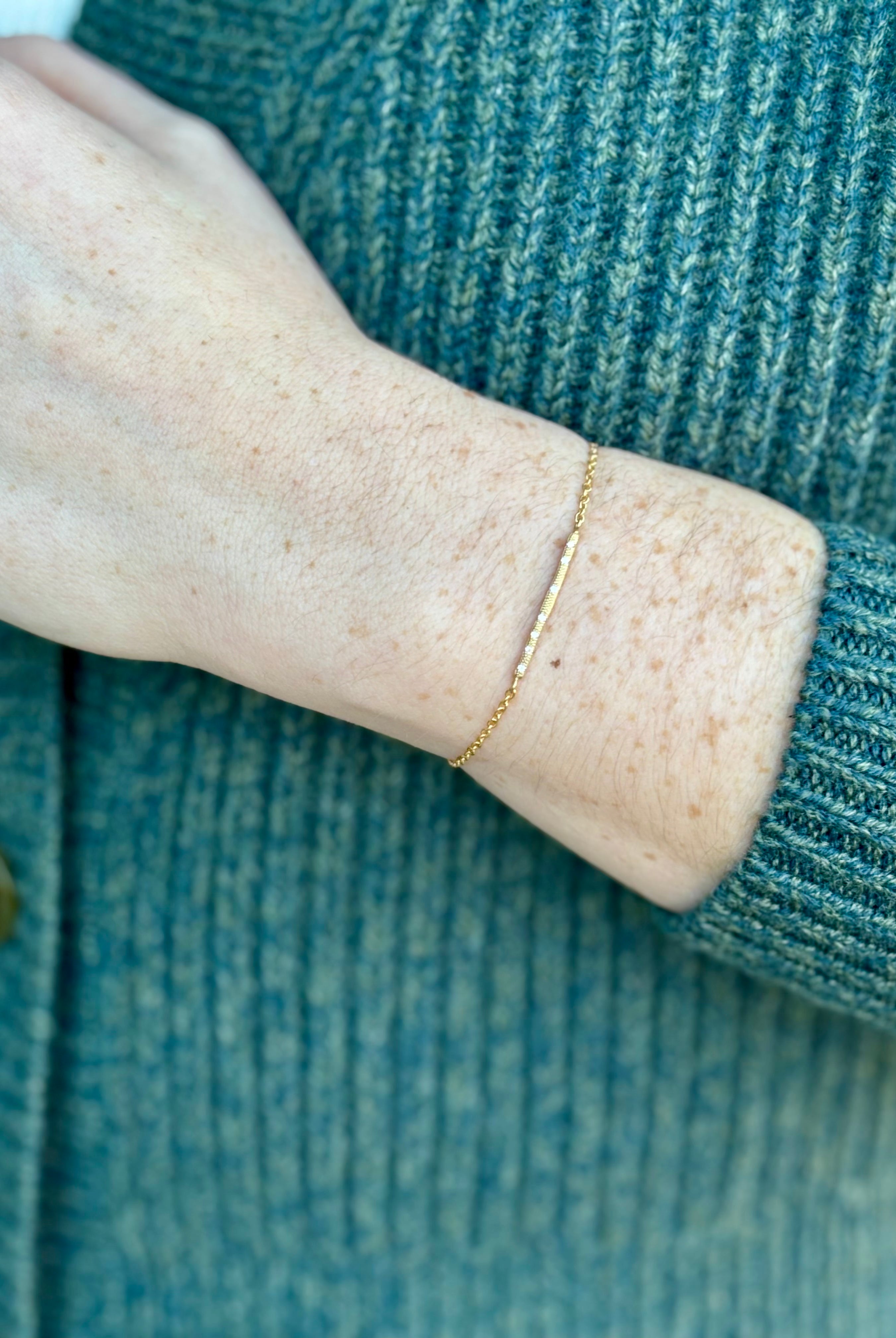 Image of a woman wearing designer Anne Sportun 18 carat gold diamond stardust bracelet single bar with hammered texture and adjustable clasp