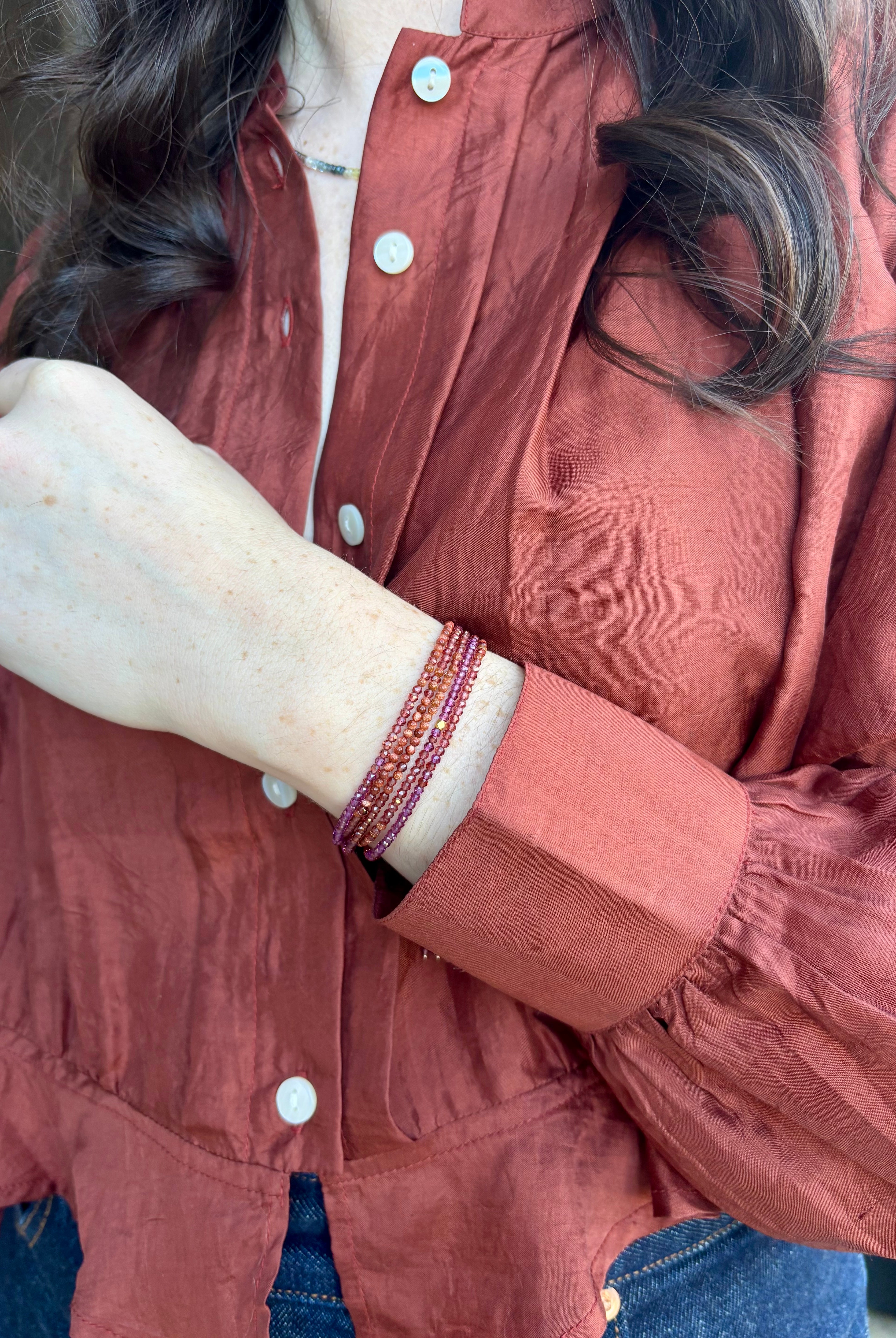 Image of woman wearing designer Anne Sportun ombre wine garnet wrap bracelet with 18 carat yellow gold hardware