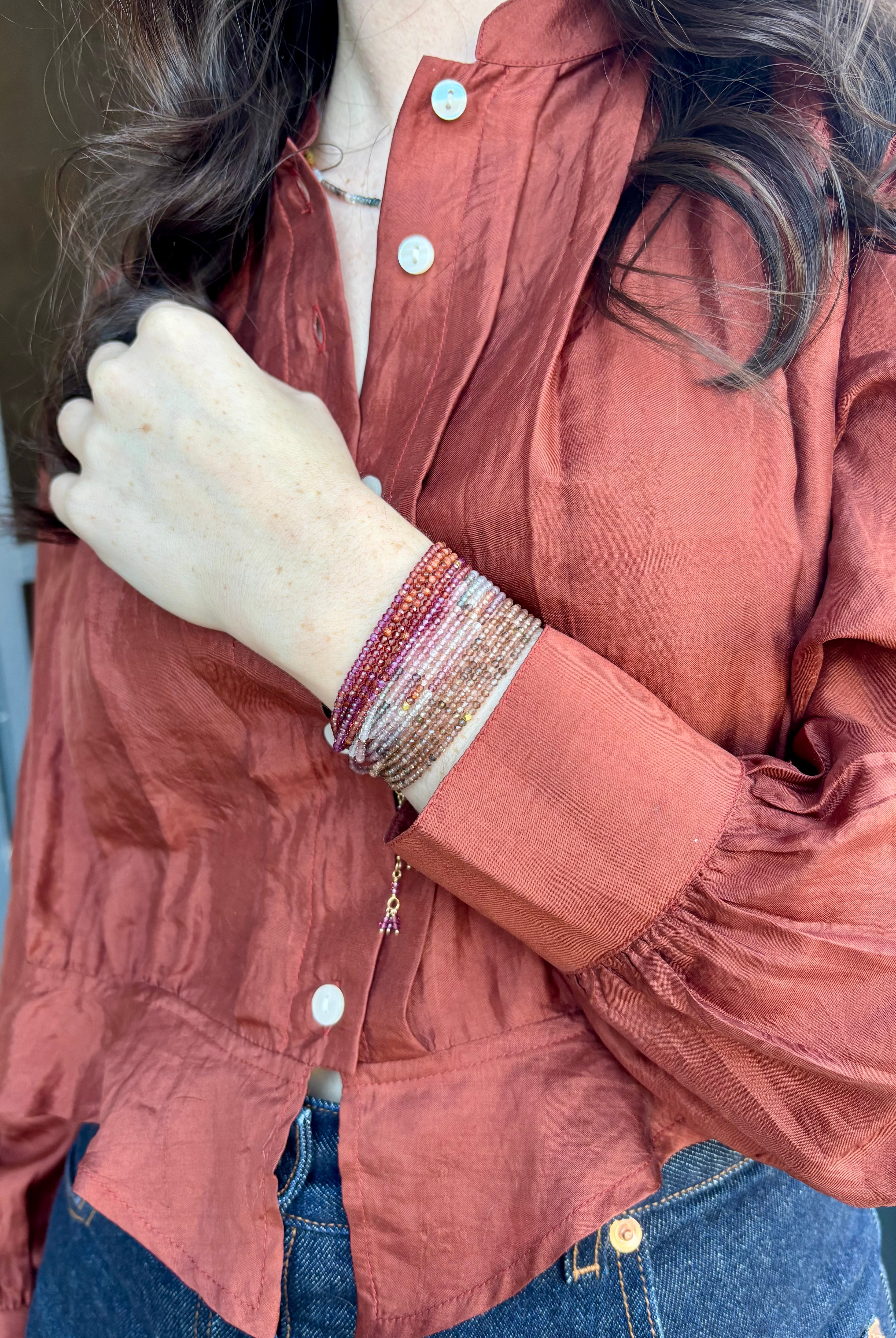 Image of woman wearing designer Anne Sportun ombre wine garnet wrap bracelet stacked with the multicolor spinel and brown garnet bracelets