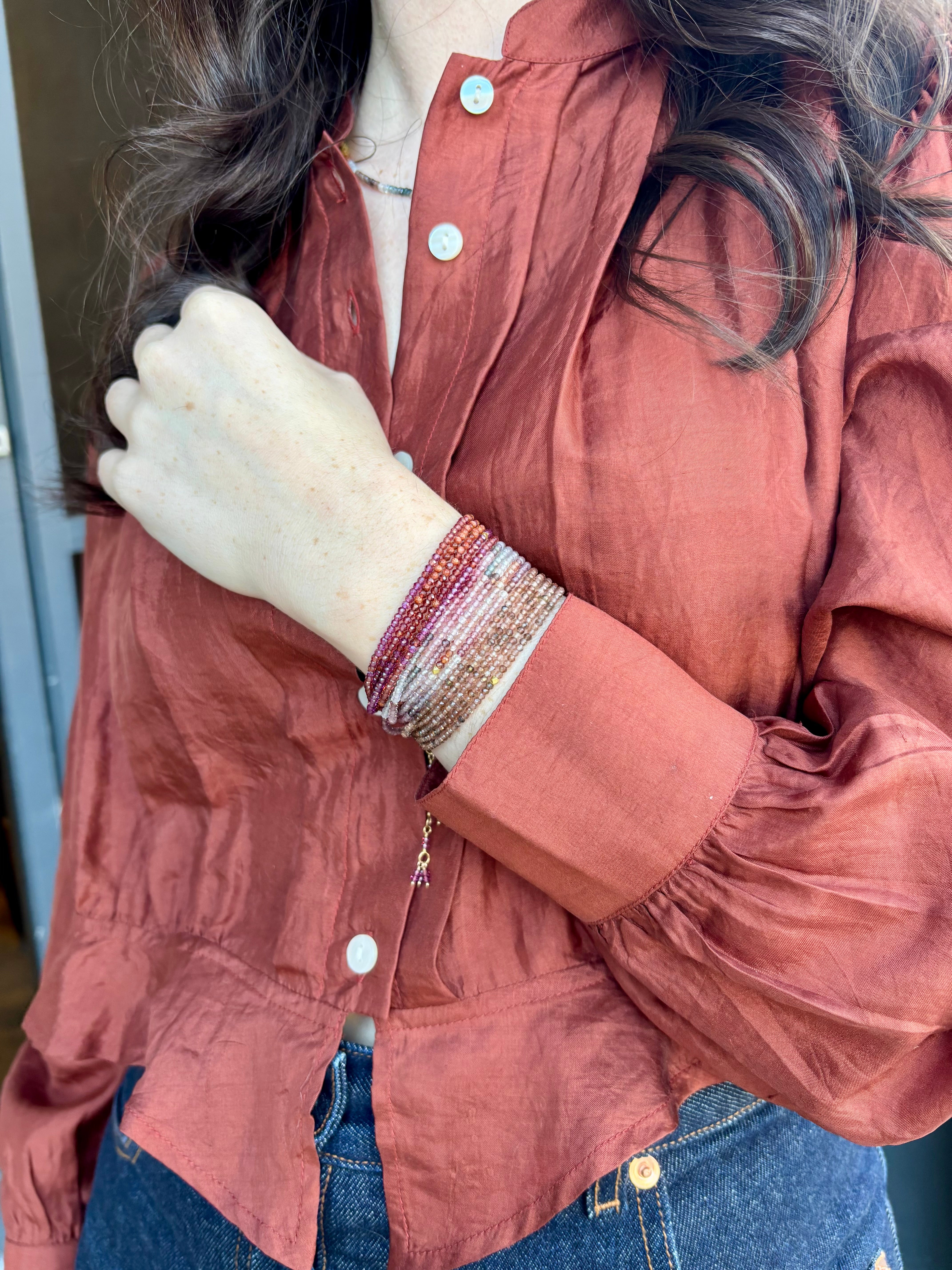 Image of woman wearing designer Anne Sportun ombre wine garnet wrap bracelet stacked with the multicolor spinel and brown garnet bracelets