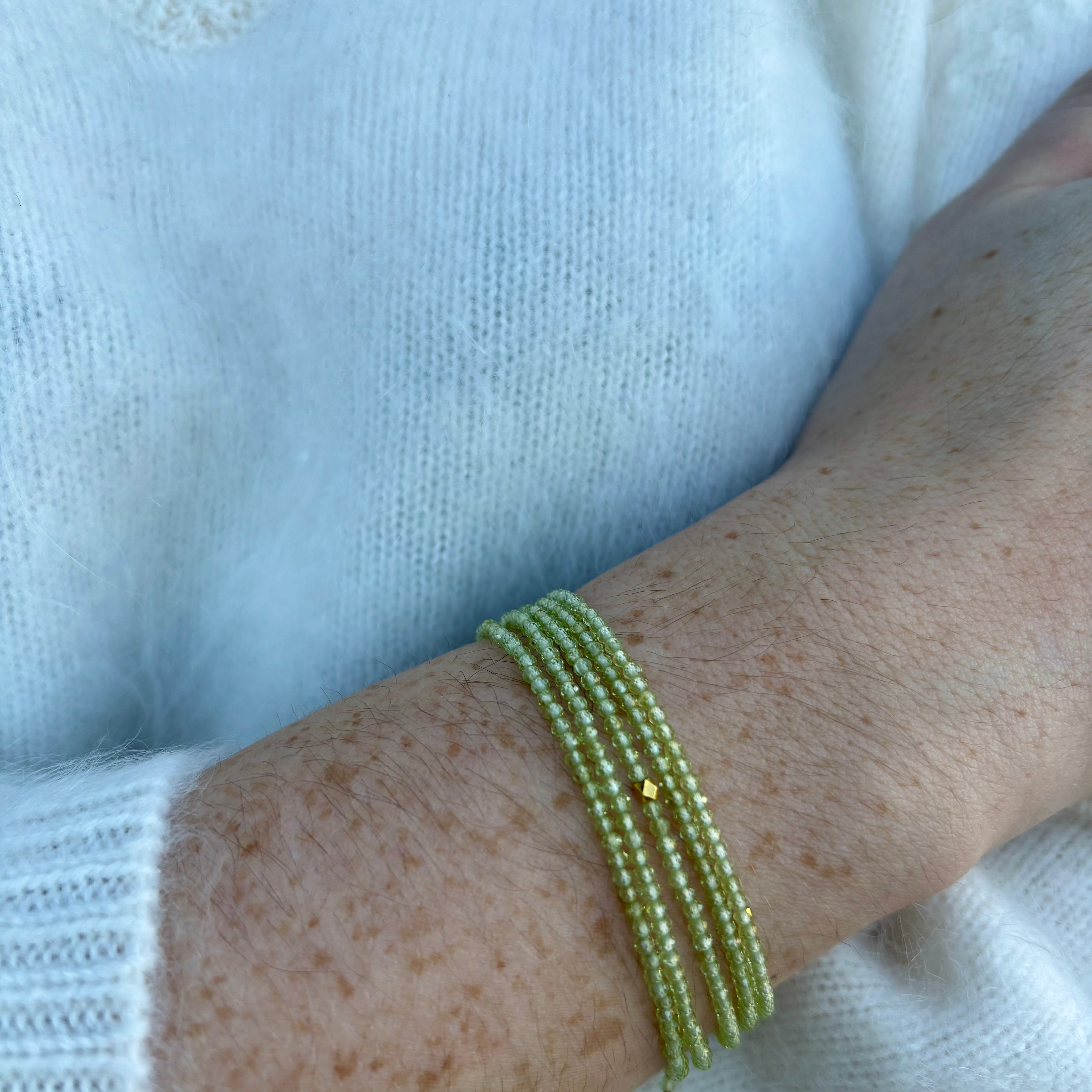 Image of a woman wearing premium peridot and gold bracelet that can also be worn as a necklace by Canadian designer Anne Sportun