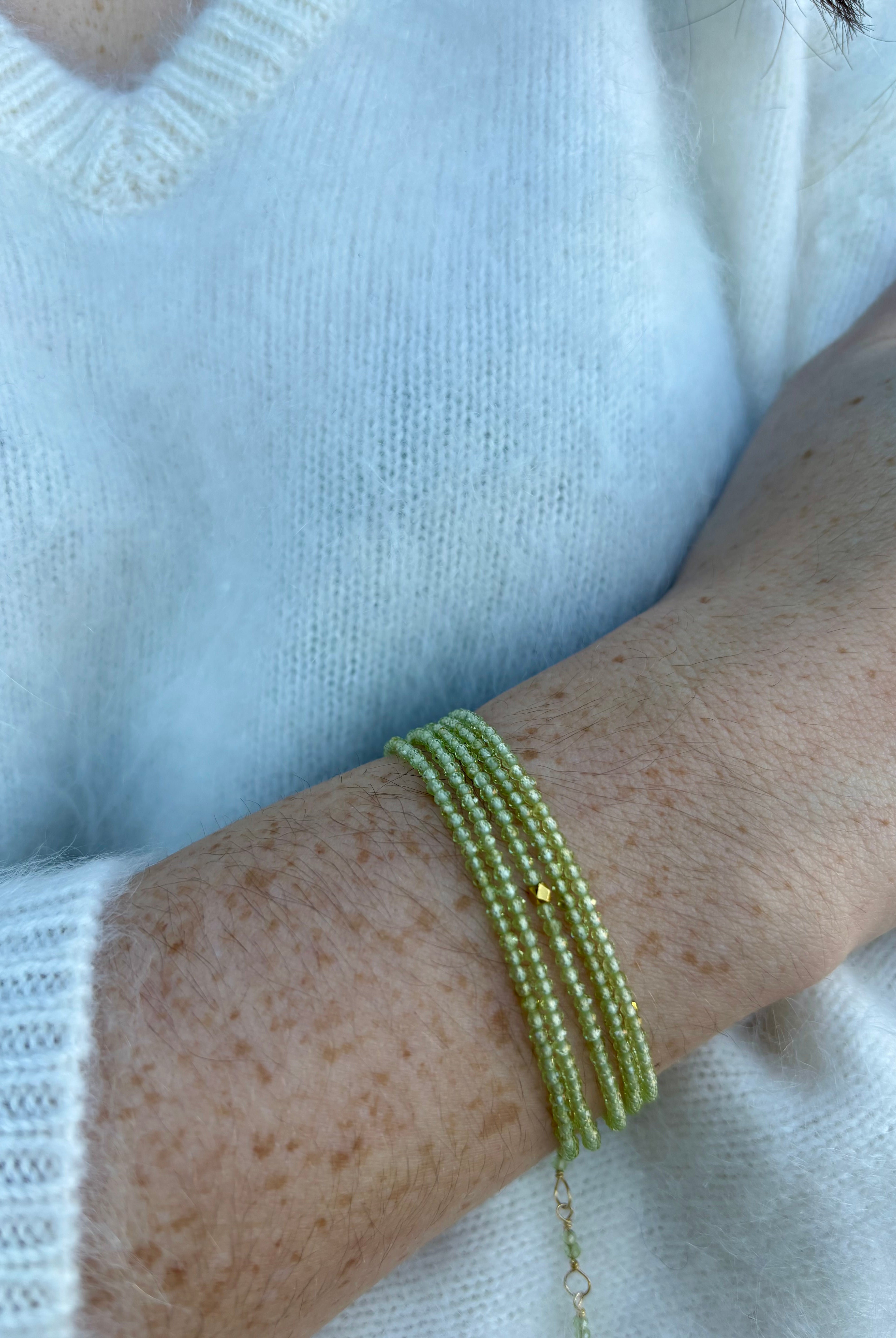Image of a woman wearing premium peridot and gold bracelet that can also be worn as a necklace by Canadian designer Anne Sportun