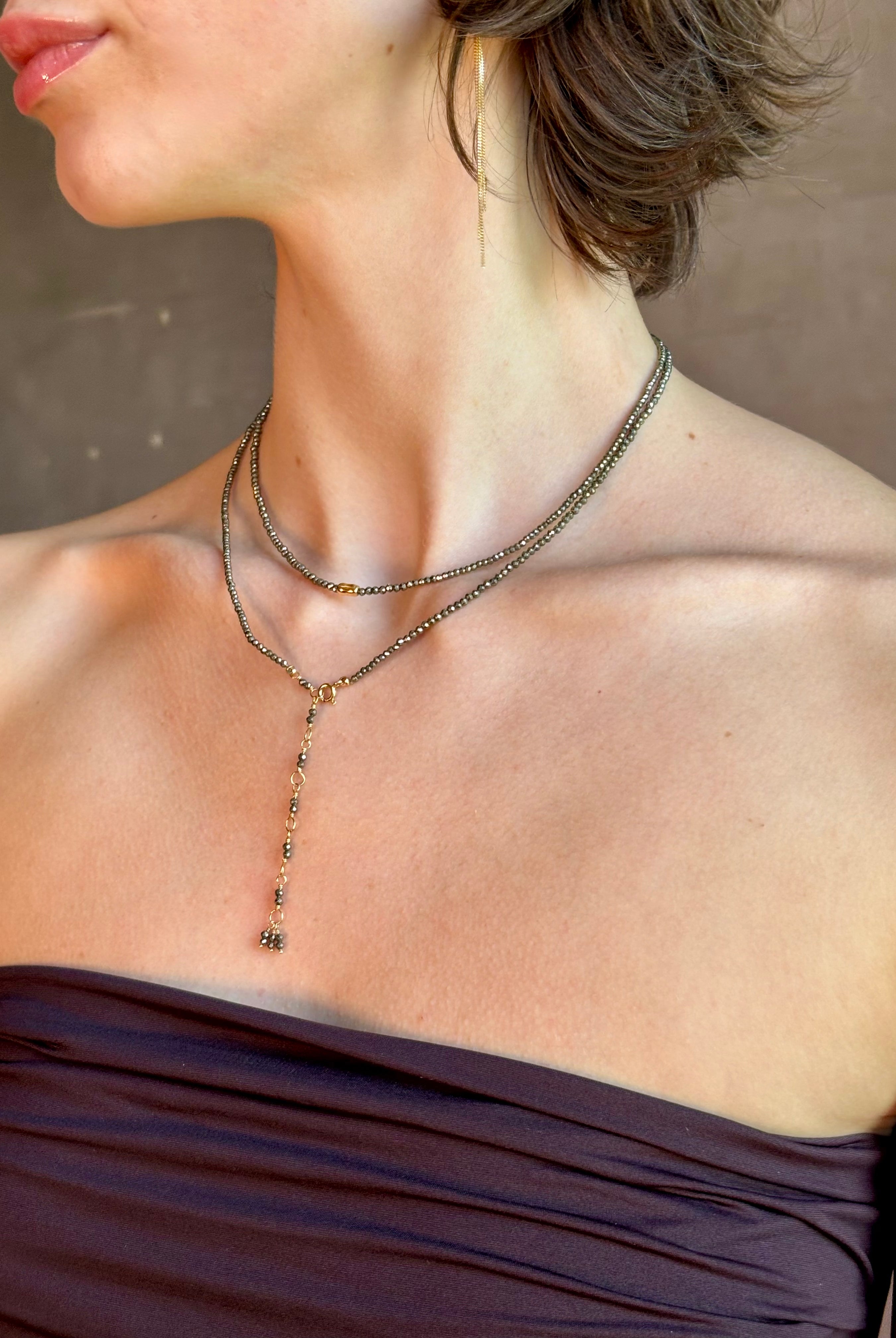 Woman wearing Pyrite River wrap Bracelet from Canadian fine jewelry artist Anne Sportun with pyrite and 18k yellow gold beads that can double as a necklace perfect for travel