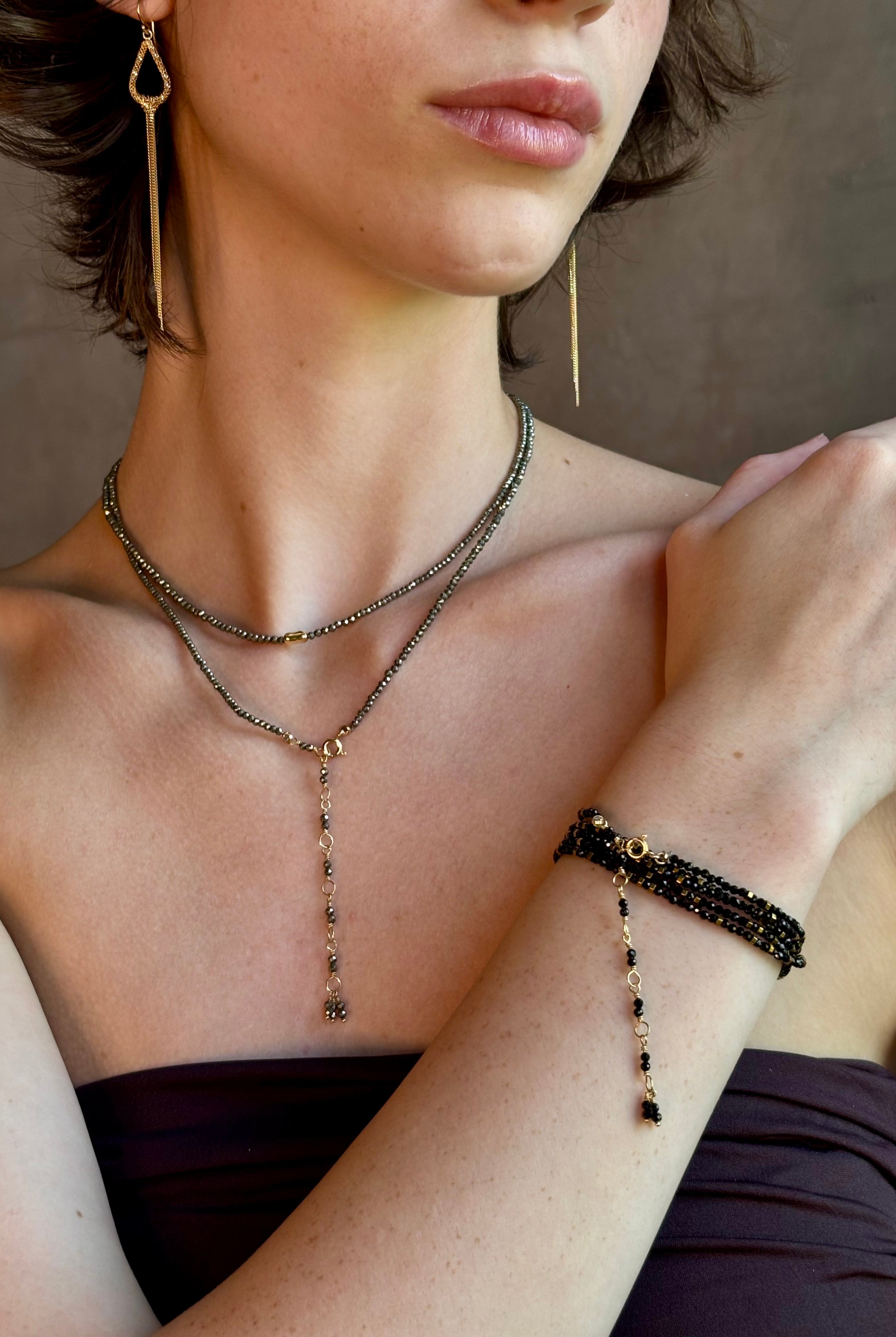 Woman wearing Pyrite River wrap Bracelet from Canadian fine jewelry artist Anne Sportun with pyrite and 18k yellow gold beads that can double as a necklace perfect for travel