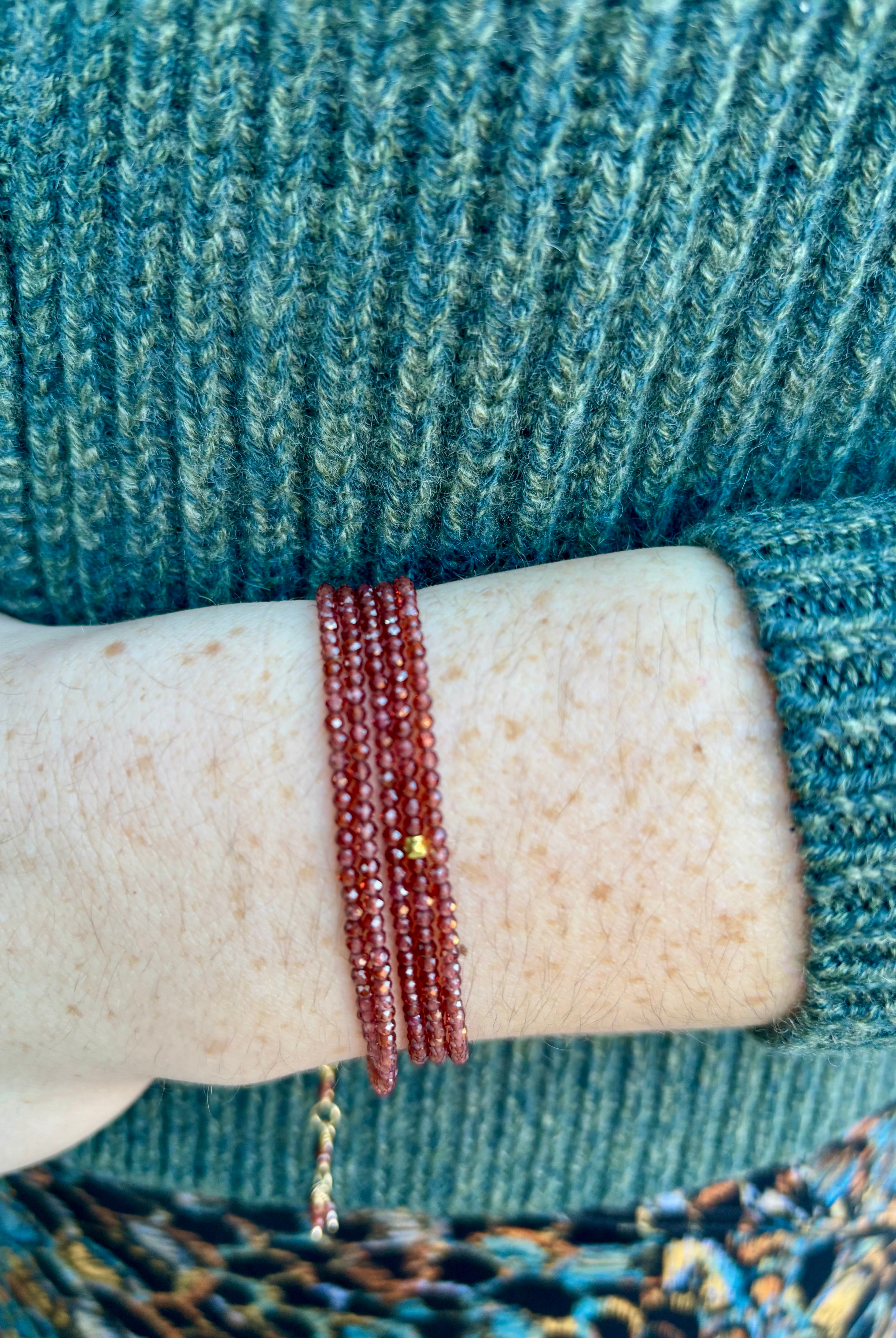 Image of a woman wearing fine jewelry designer Anne Sportun red garnet wrap bracelet with adjustable 18 carat yellow gold clasp