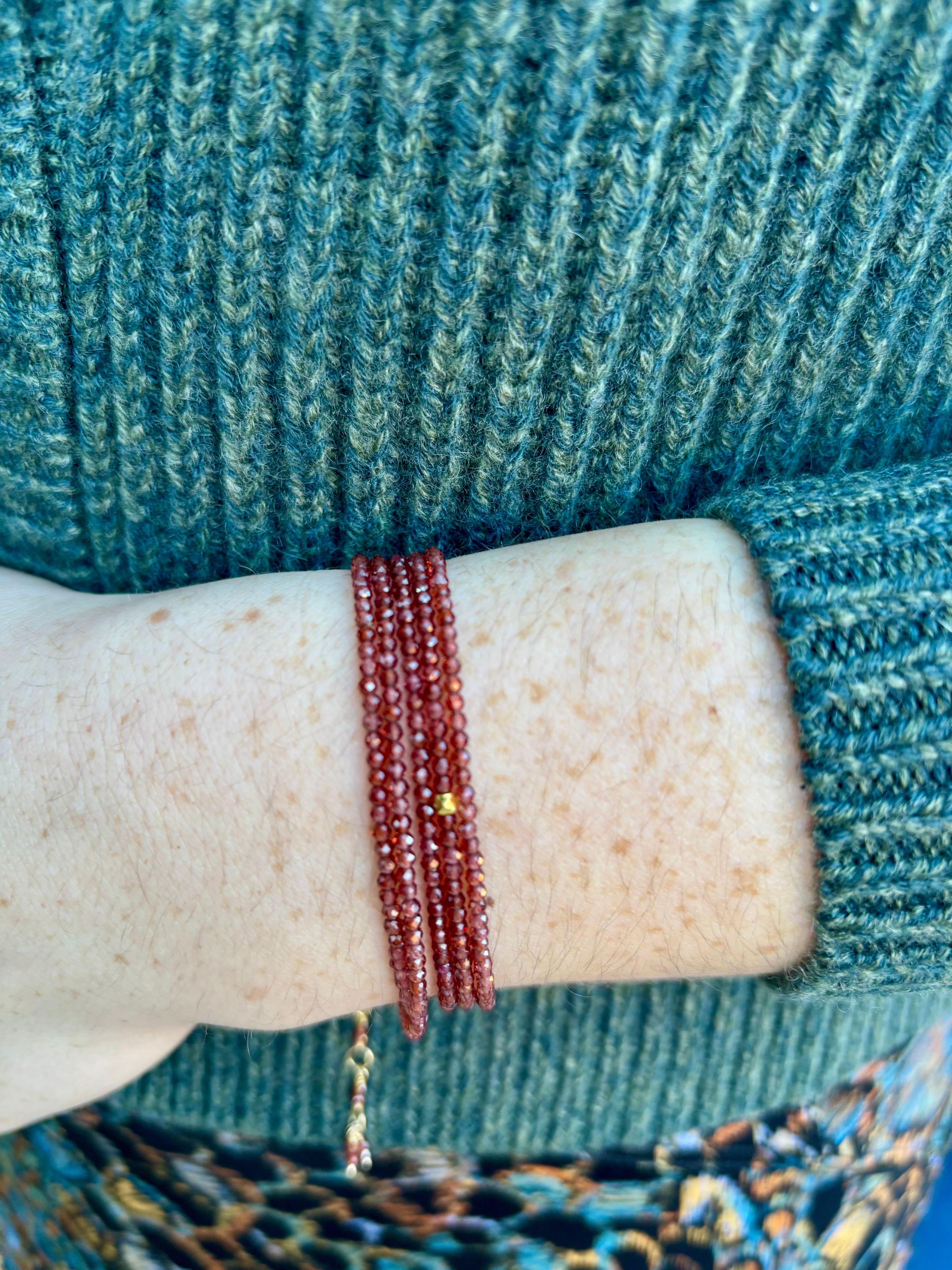 Image of a woman wearing fine jewelry designer Anne Sportun red garnet wrap bracelet with adjustable 18 carat yellow gold clasp
